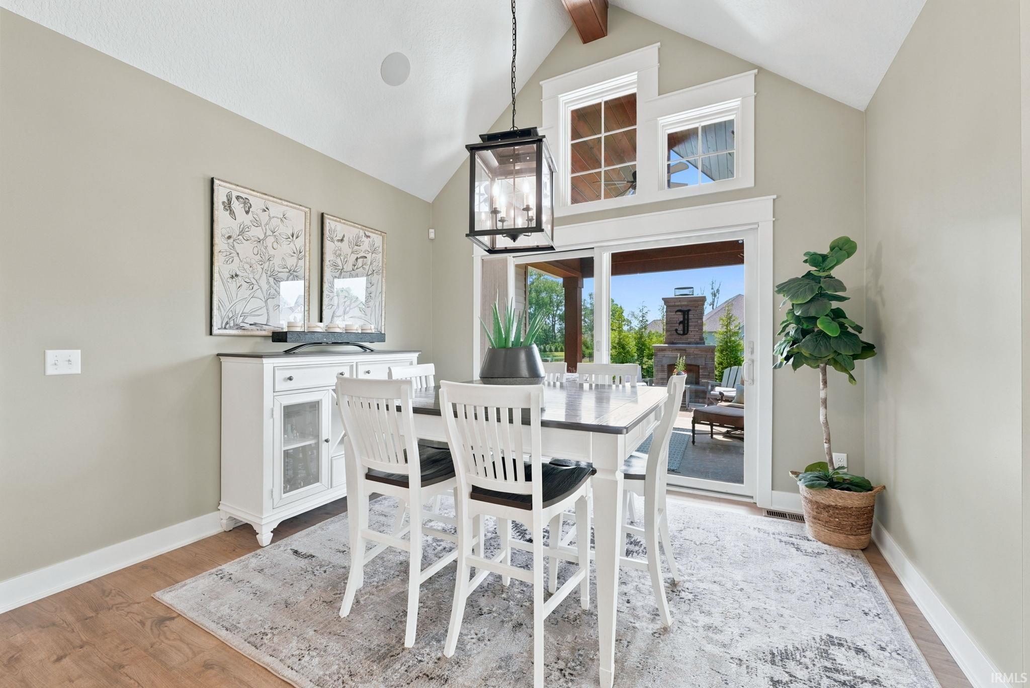 Vaulted ceiling with exposed wood beam, wood-finish flooring, and a sliding glass door providing outdoor access