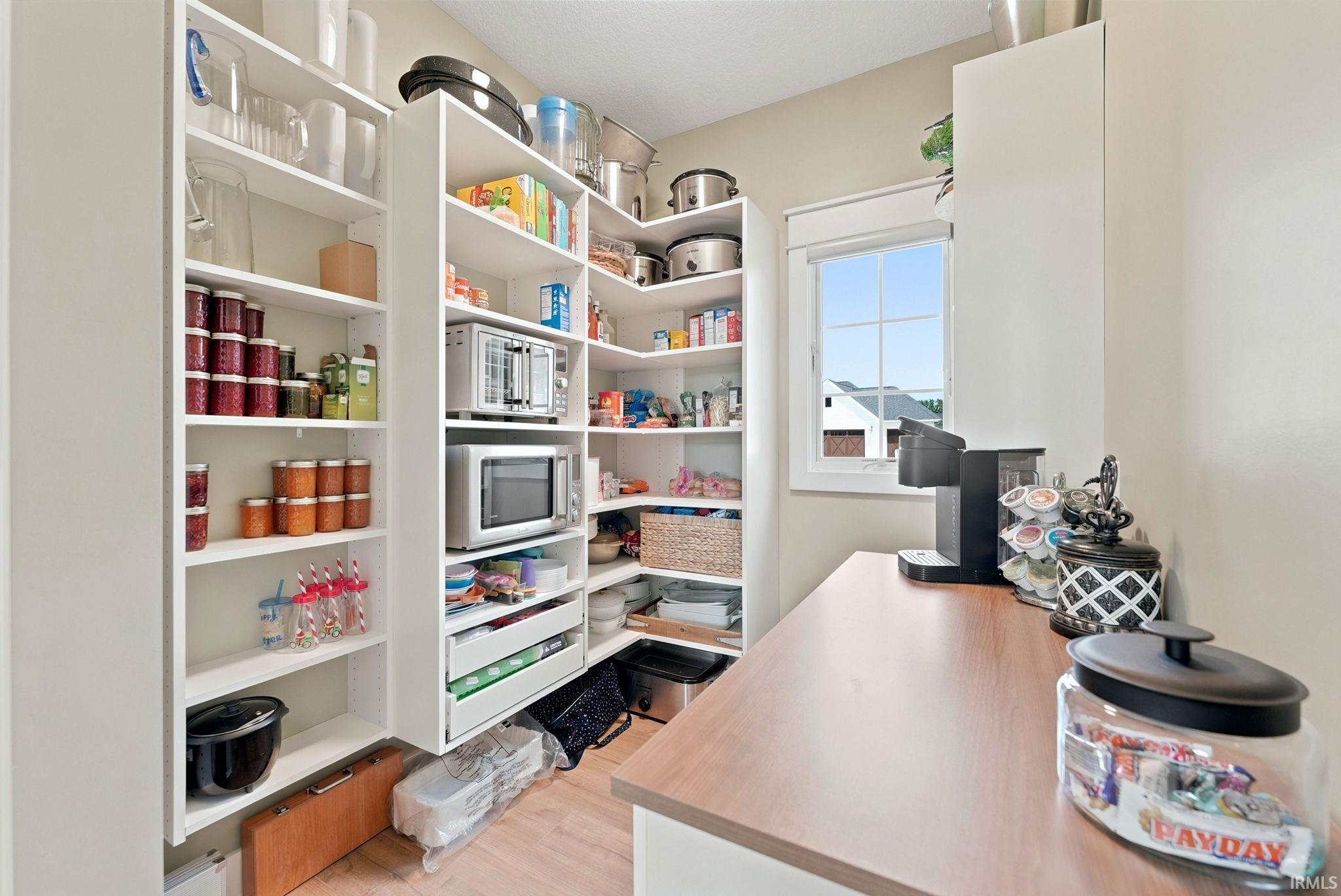 Custom pantry featuring extensive built-in shelving, integrated drawers, a built-in countertop, and a window for natural light