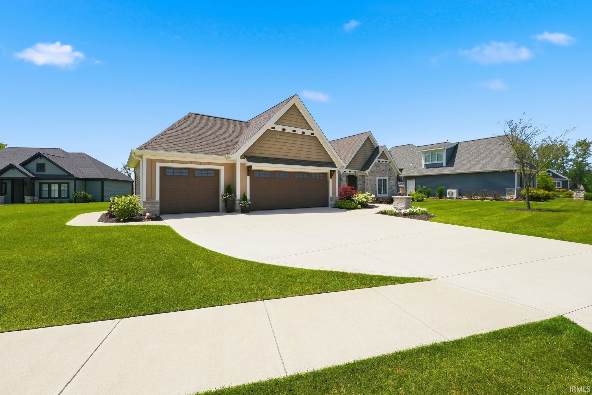 Contemporary home featuring a stone and siding exterior, a two-car garage with panel doors, a concrete driveway, and a concrete sidewalk