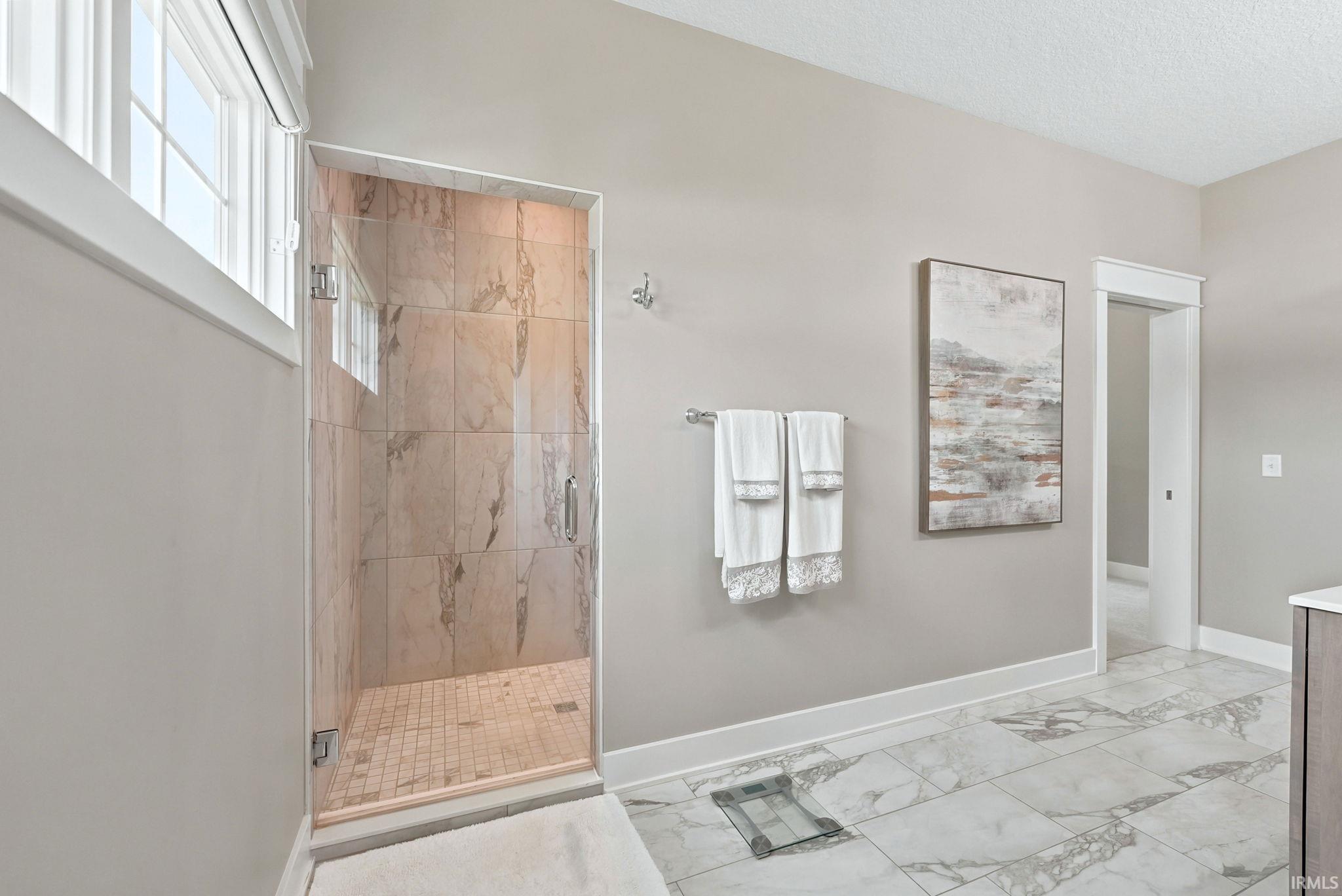 Shower enclosure featuring a frameless glass door, large format tile interior, and mosaic tile floor