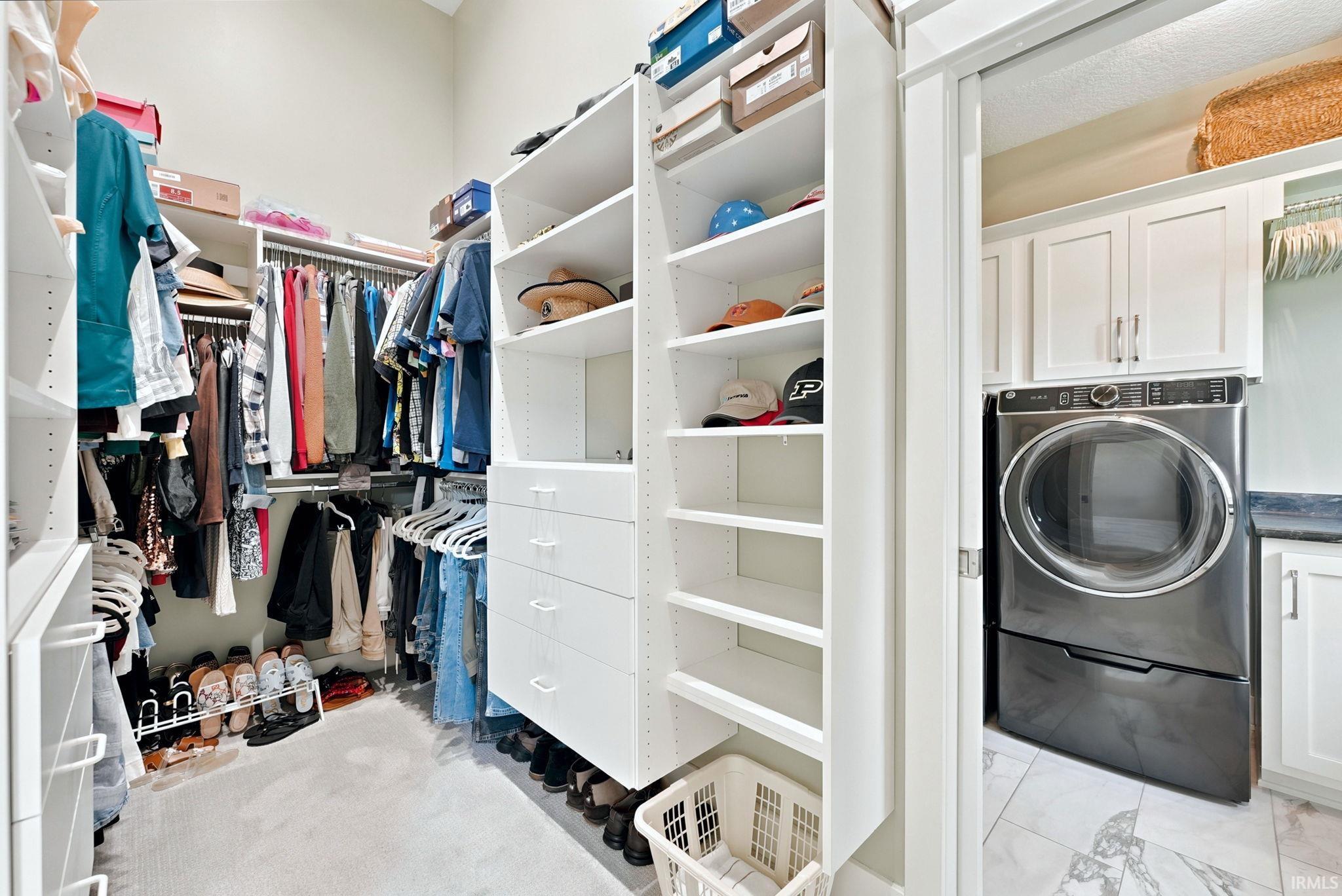 Walk-in closet featuring extensive built-in shelving, multiple hanging rods, and integrated drawers