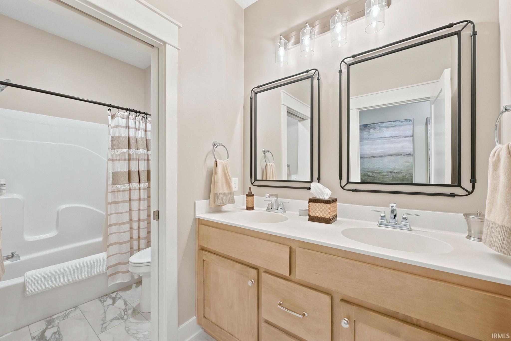 Dual vanity with light wood cabinetry, white countertops, and chrome fixtures