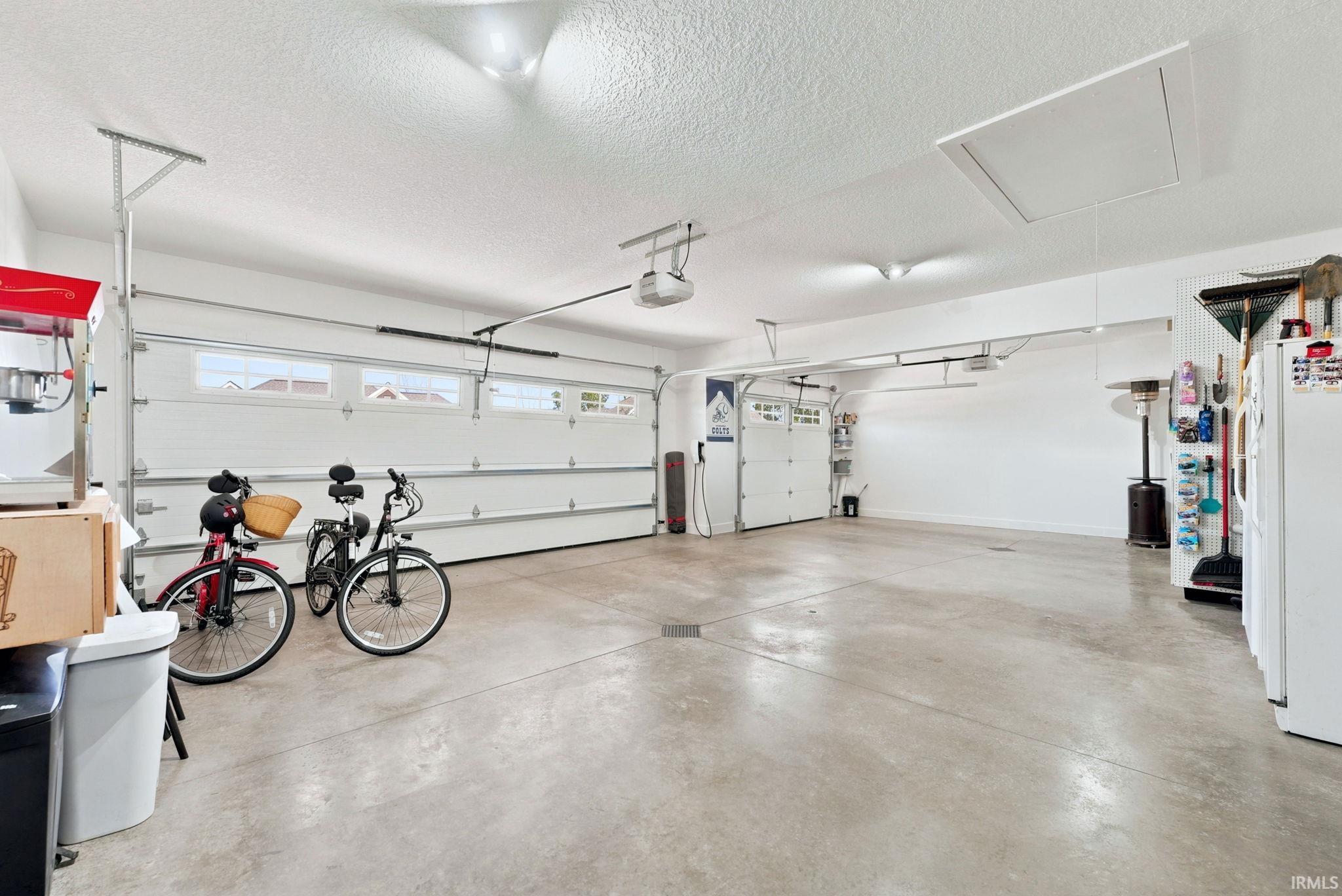 Spacious garage featuring two overhead doors, concrete flooring, and ceiling-mounted lighting