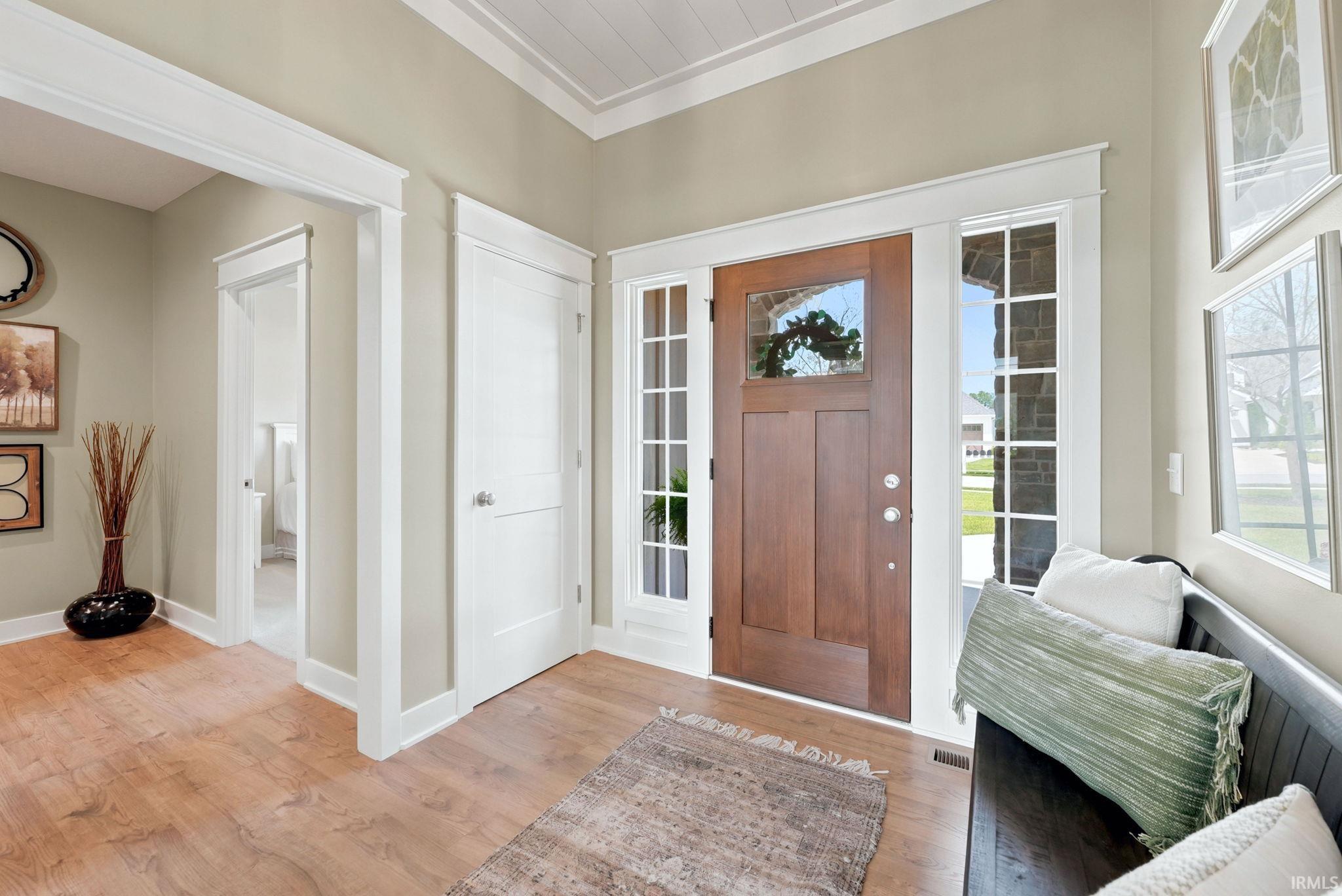 Entryway with a craftsman-style wood-finish door, sidelight windows, and transom window