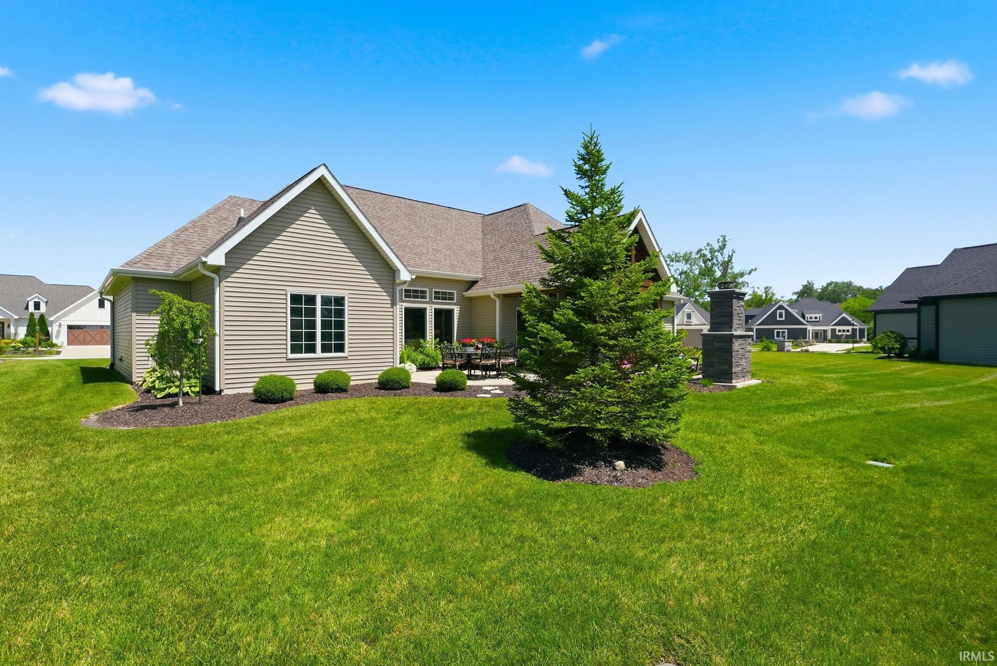 Expansive green lawn surrounds a contemporary residence with light-toned siding and a brown shingle roof