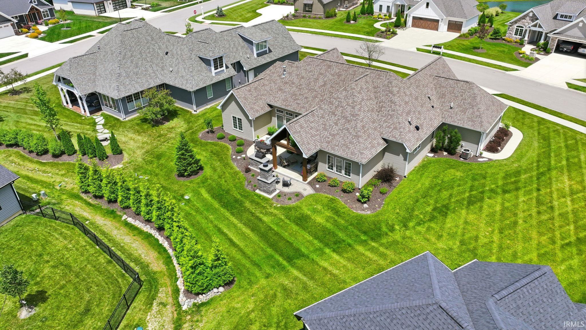 Expansive backyard featuring a manicured lawn, established landscaping, and a covered outdoor living area