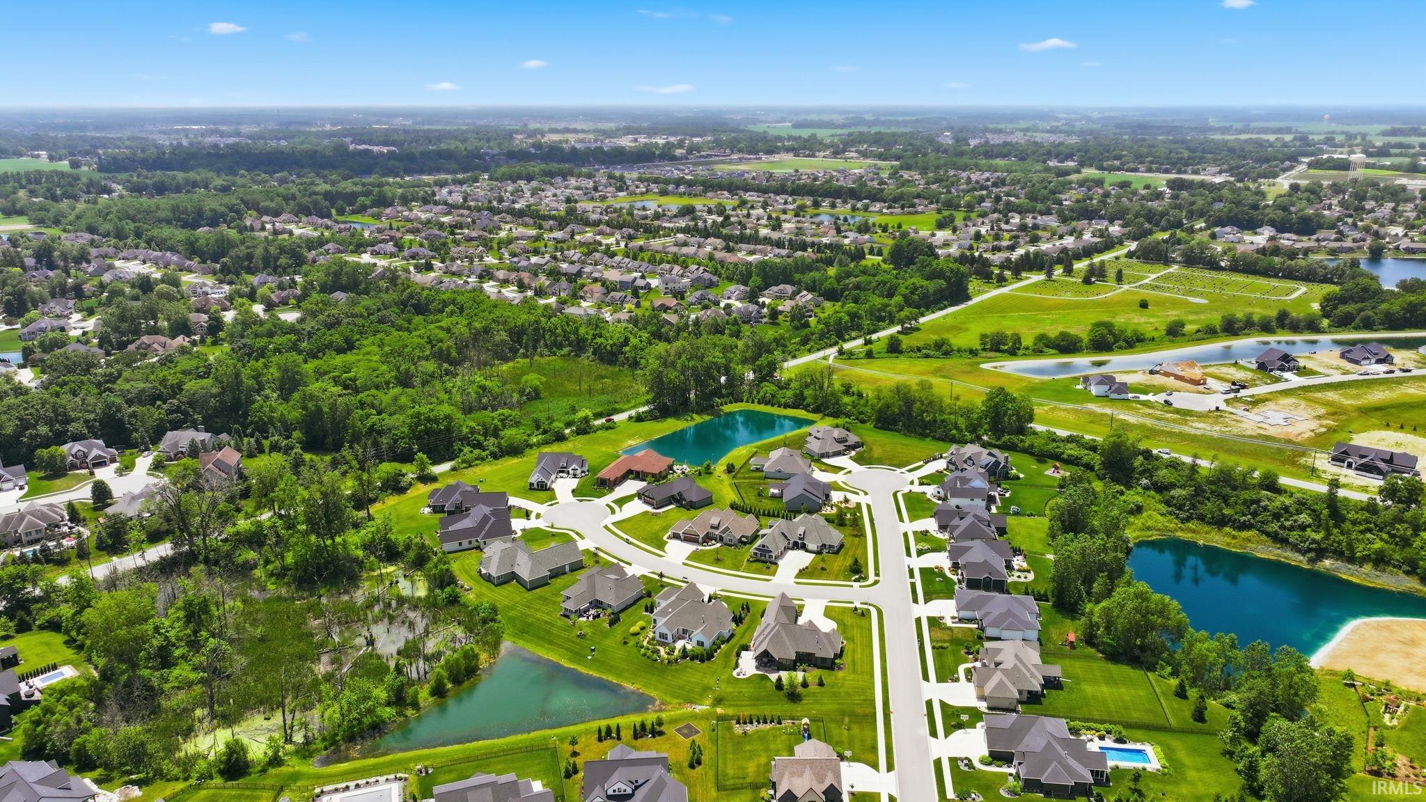 Aerial perspective showcasing a residential development with multiple private ponds, verdant treelines, and expansive green spaces