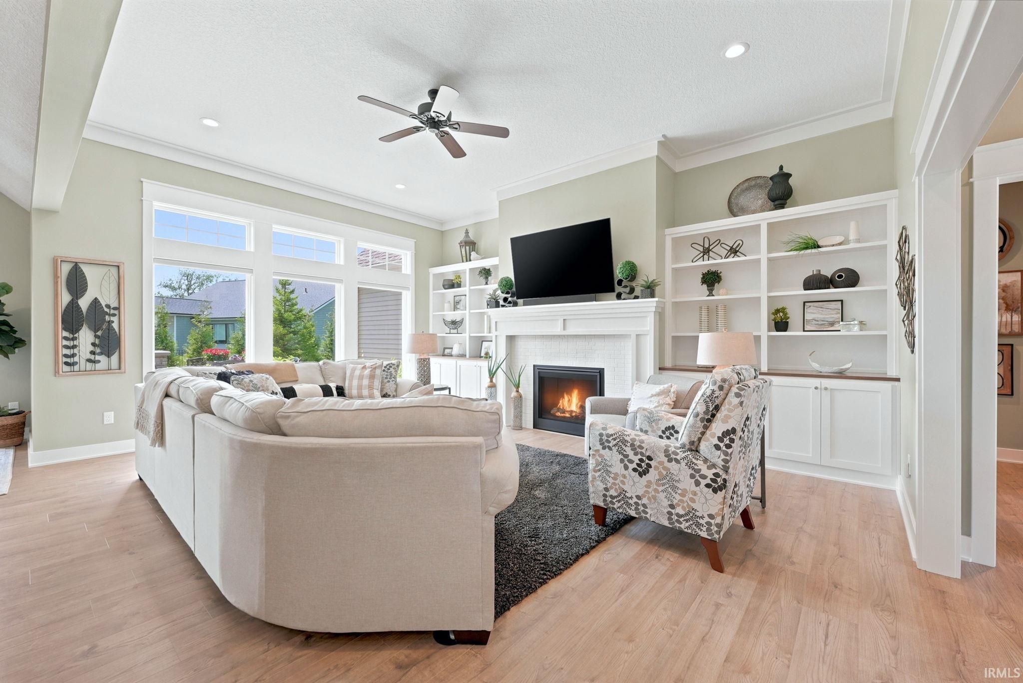 Spacious living area featuring light wood-finish flooring, a tray ceiling with a ceiling fan, and recessed lighting