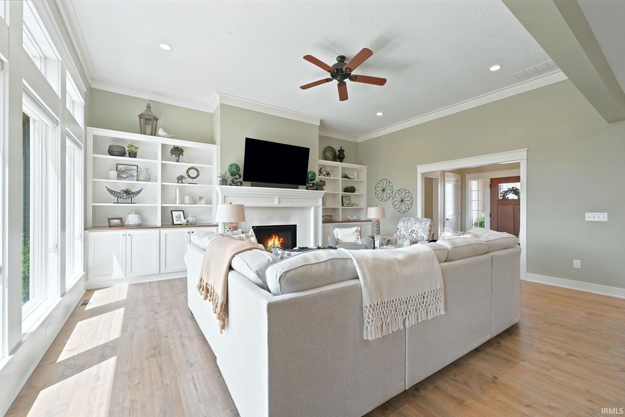 Spacious living area featuring light wood-finish flooring, a contemporary ceiling fan, and recessed lighting