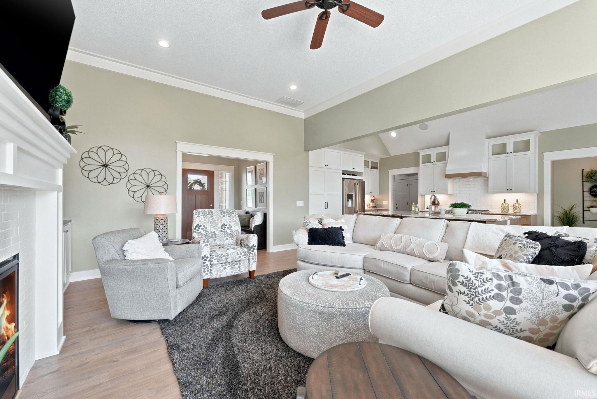 Spacious living area featuring high vaulted ceilings, recessed lighting, wood-finish flooring, and a fireplace with white tile surround