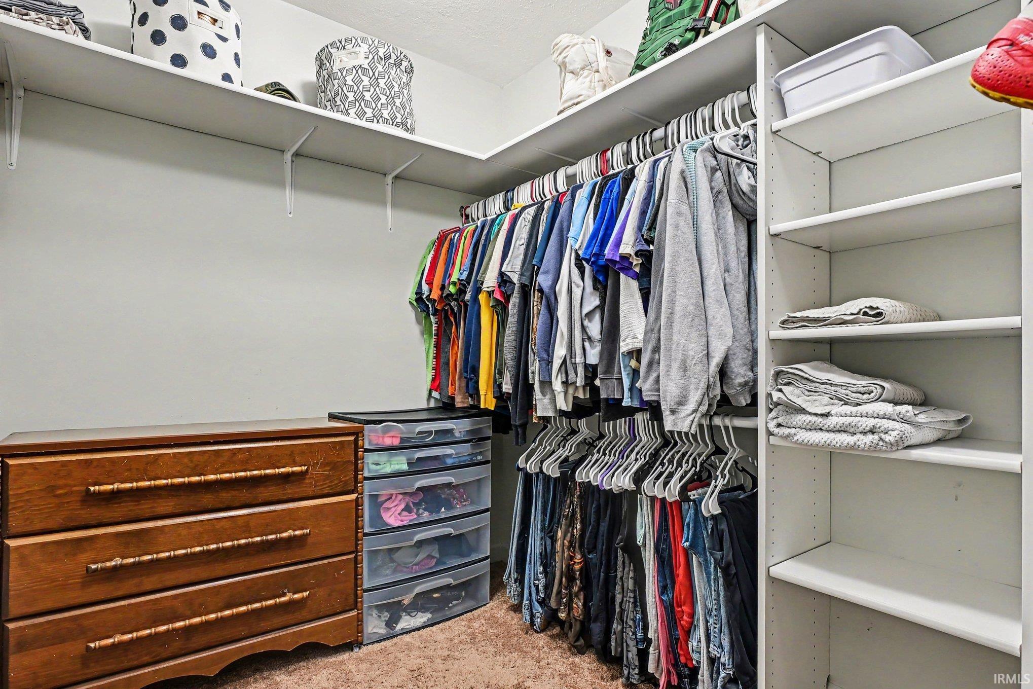 Walk-in closet featuring extensive built-in shelving, multiple hanging rods, and integrated wall-mounted storage