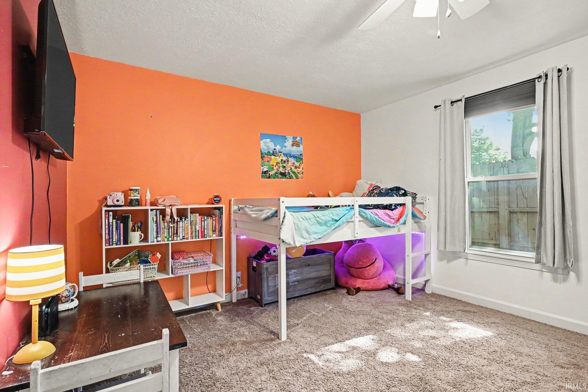 Room featuring an accent wall, carpeted flooring, a window with blinds, and a ceiling fan