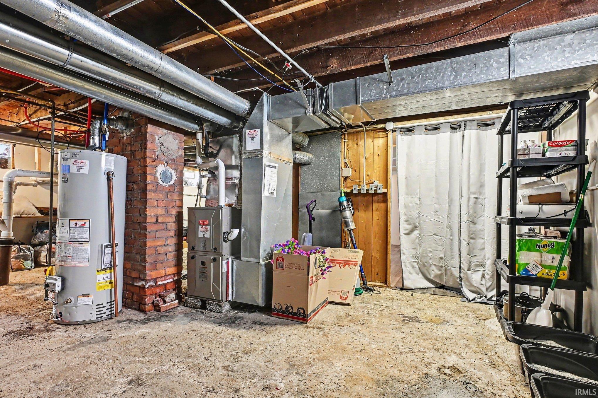 Utility area featuring a water heater, furnace, and exposed ceiling beams