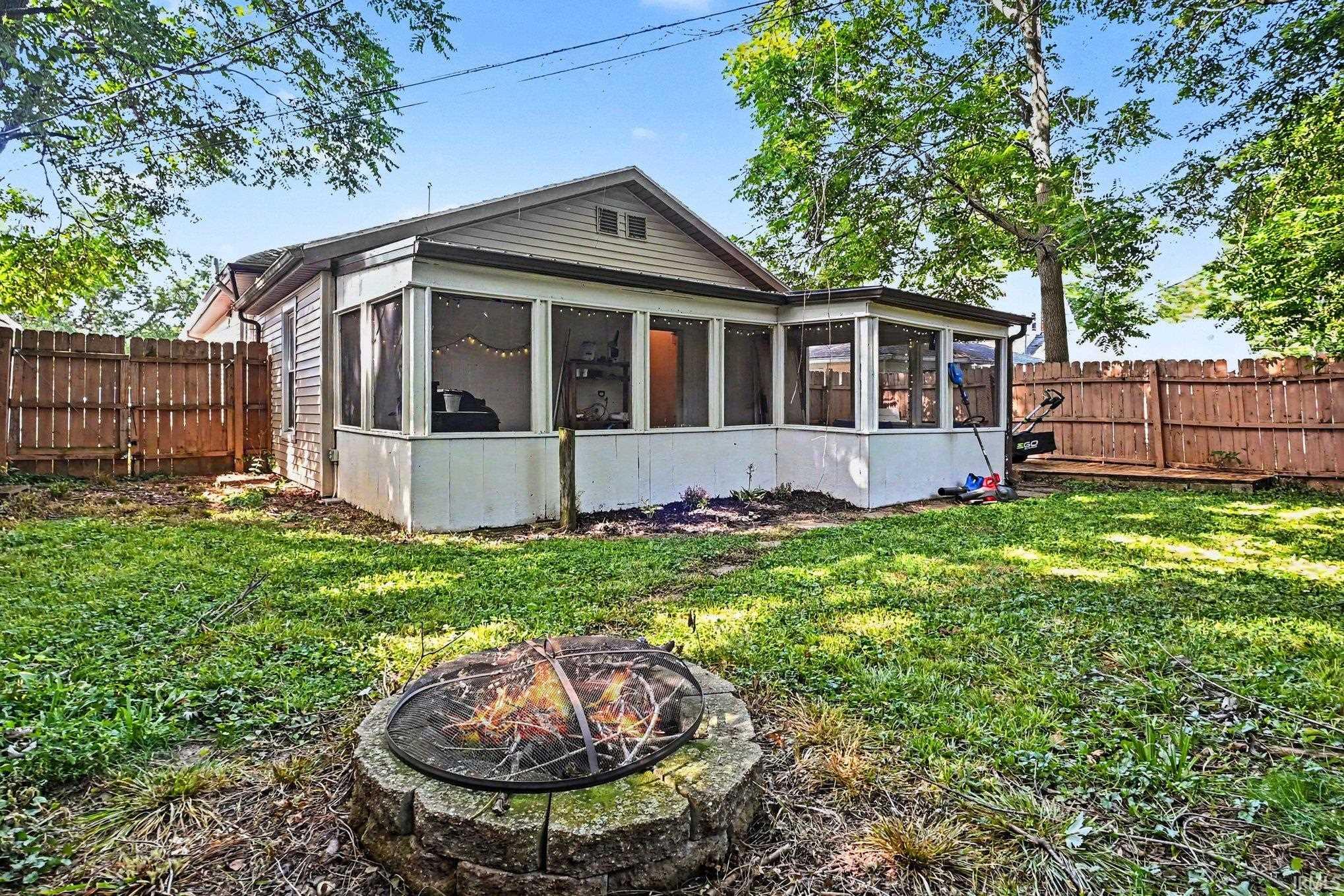 Rear exterior featuring a screened porch and a fenced yard with mature trees