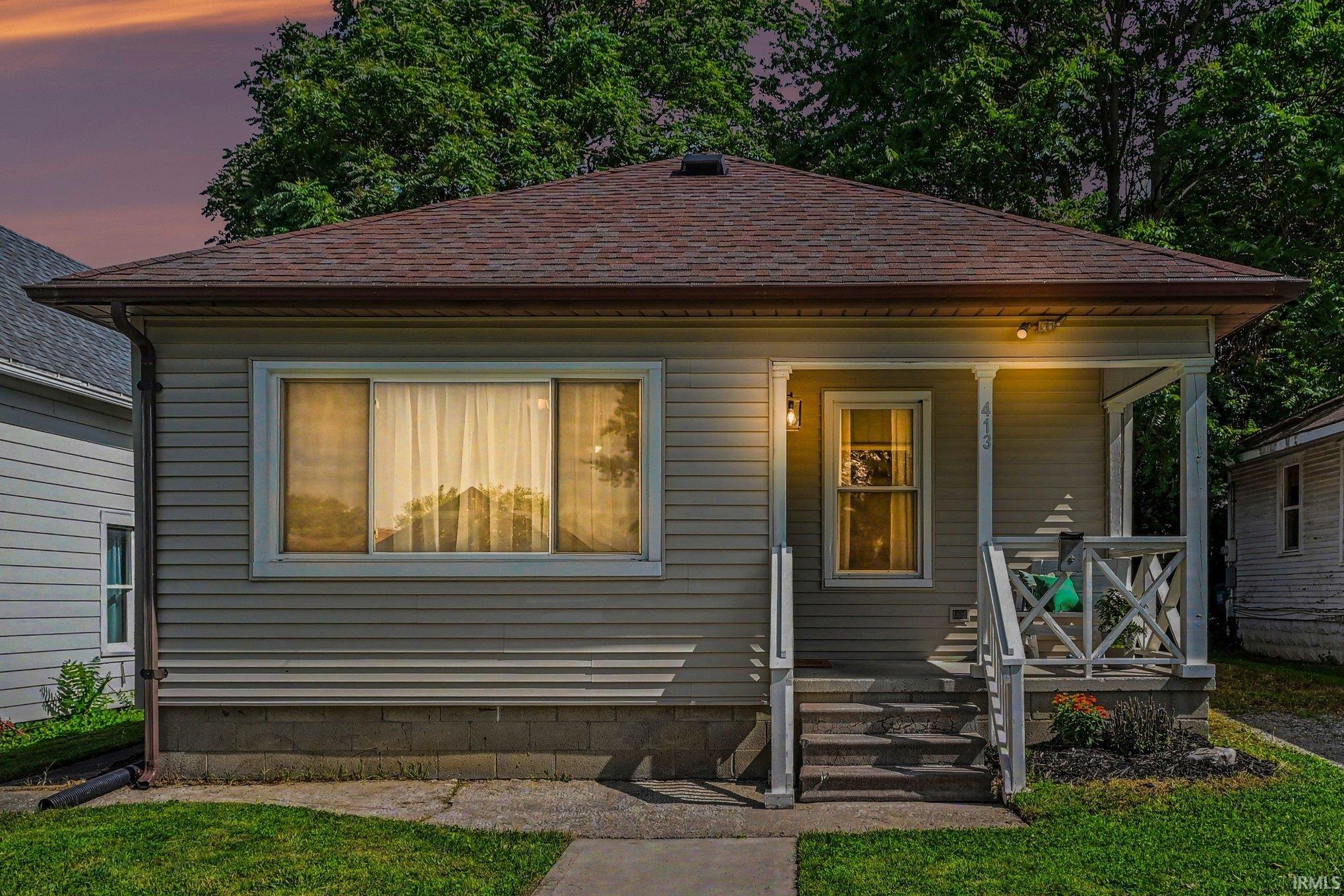 Exterior featuring horizontal siding, a covered front porch with white columns, and a shingled roof