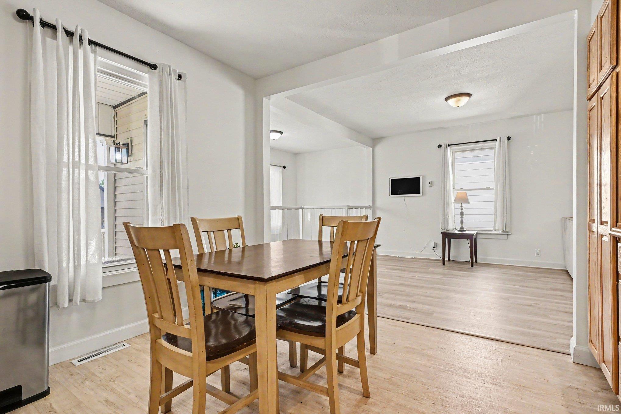 Dining area featuring wood-finish flooring, a window with a white frame, and overhead lighting