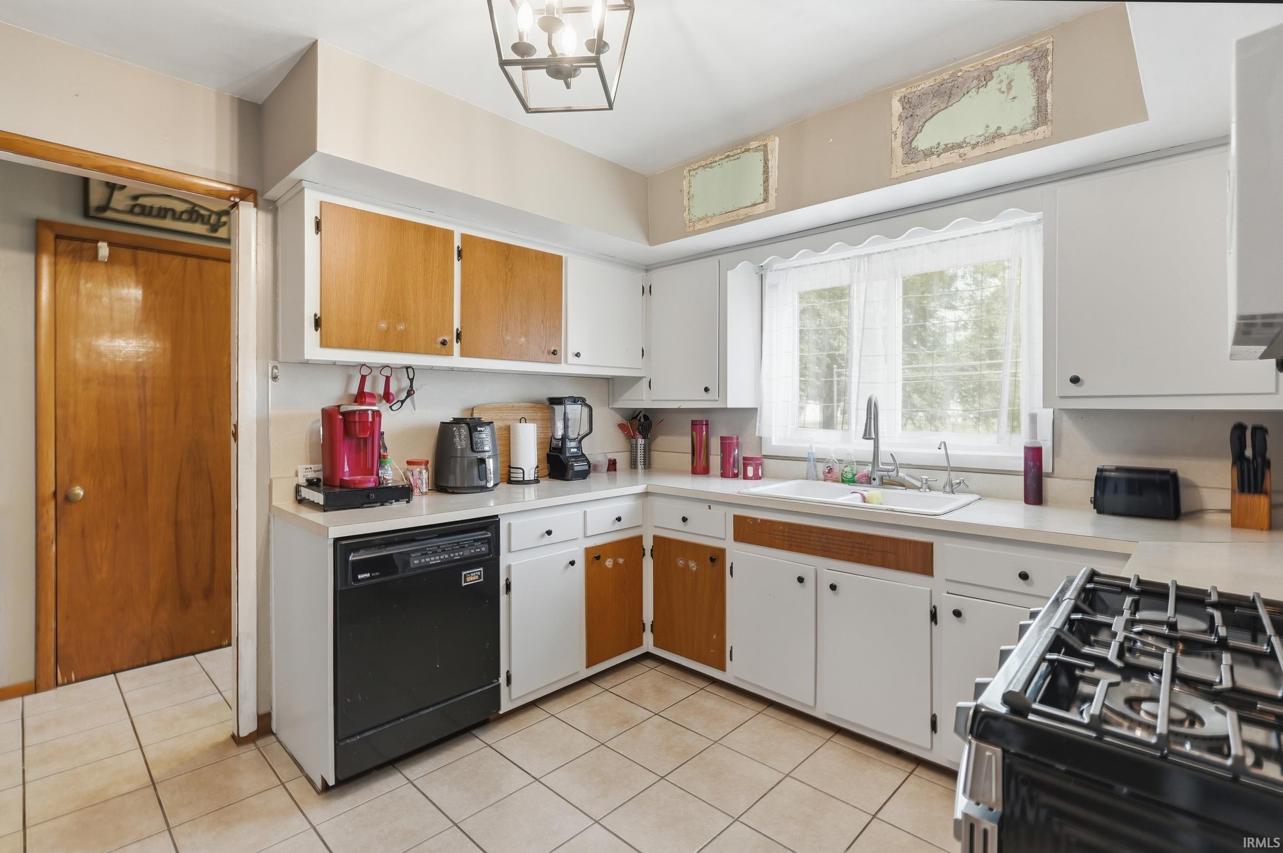 Kitchen featuring a double basin sink, white cabinetry with wood-finish accents, and tile flooring