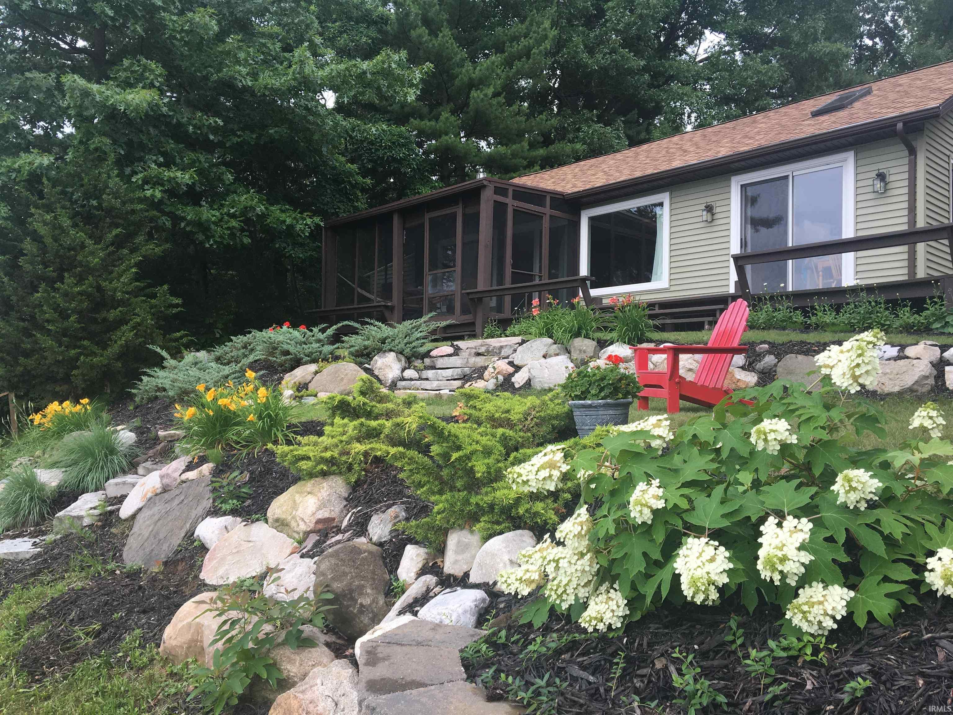 Landscaped outdoor space featuring a stone pathway, diverse plantings, and a terraced rock garden