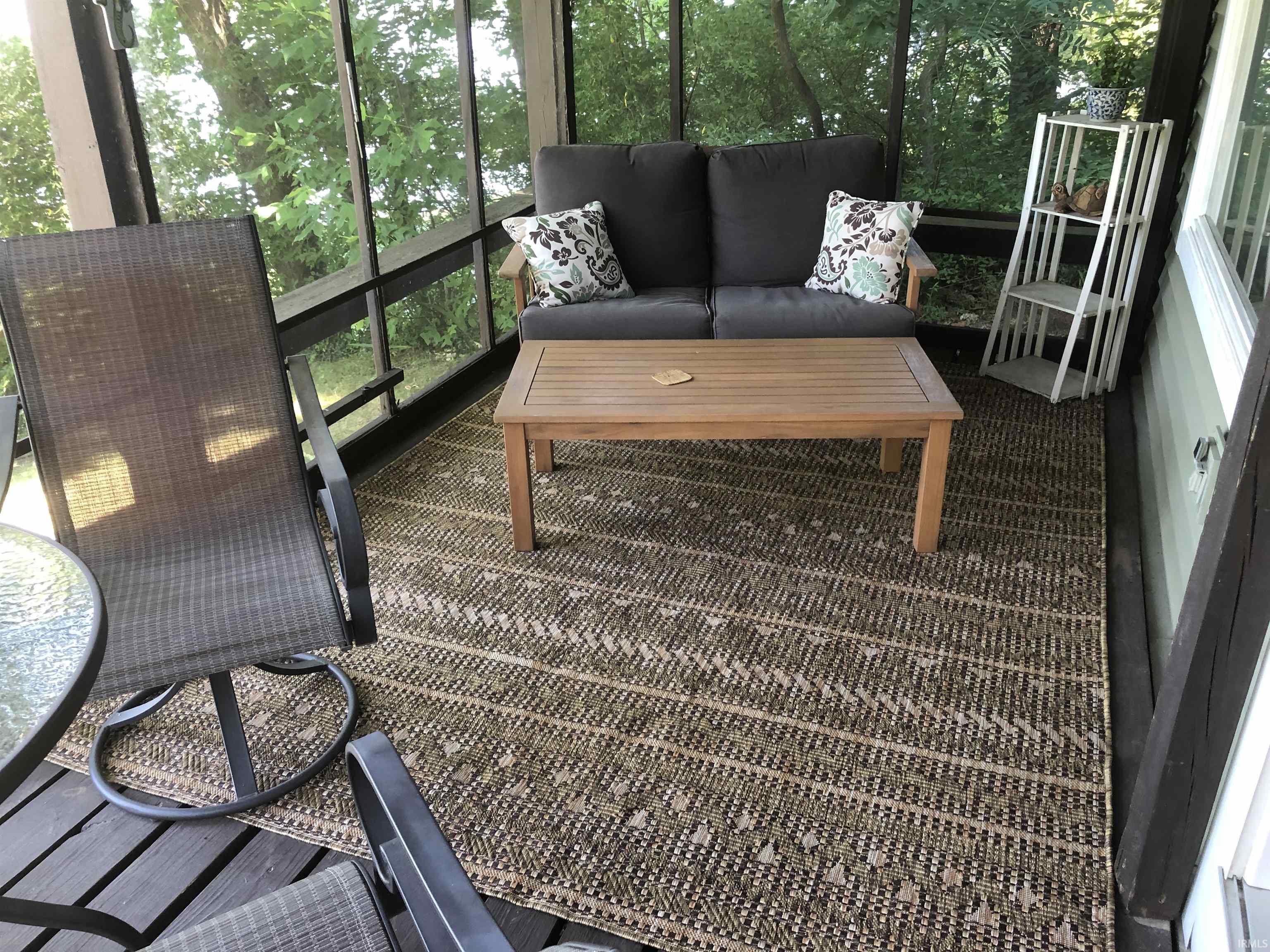 Screened porch featuring wood-finish flooring, dark framed screening, and light-colored exterior siding