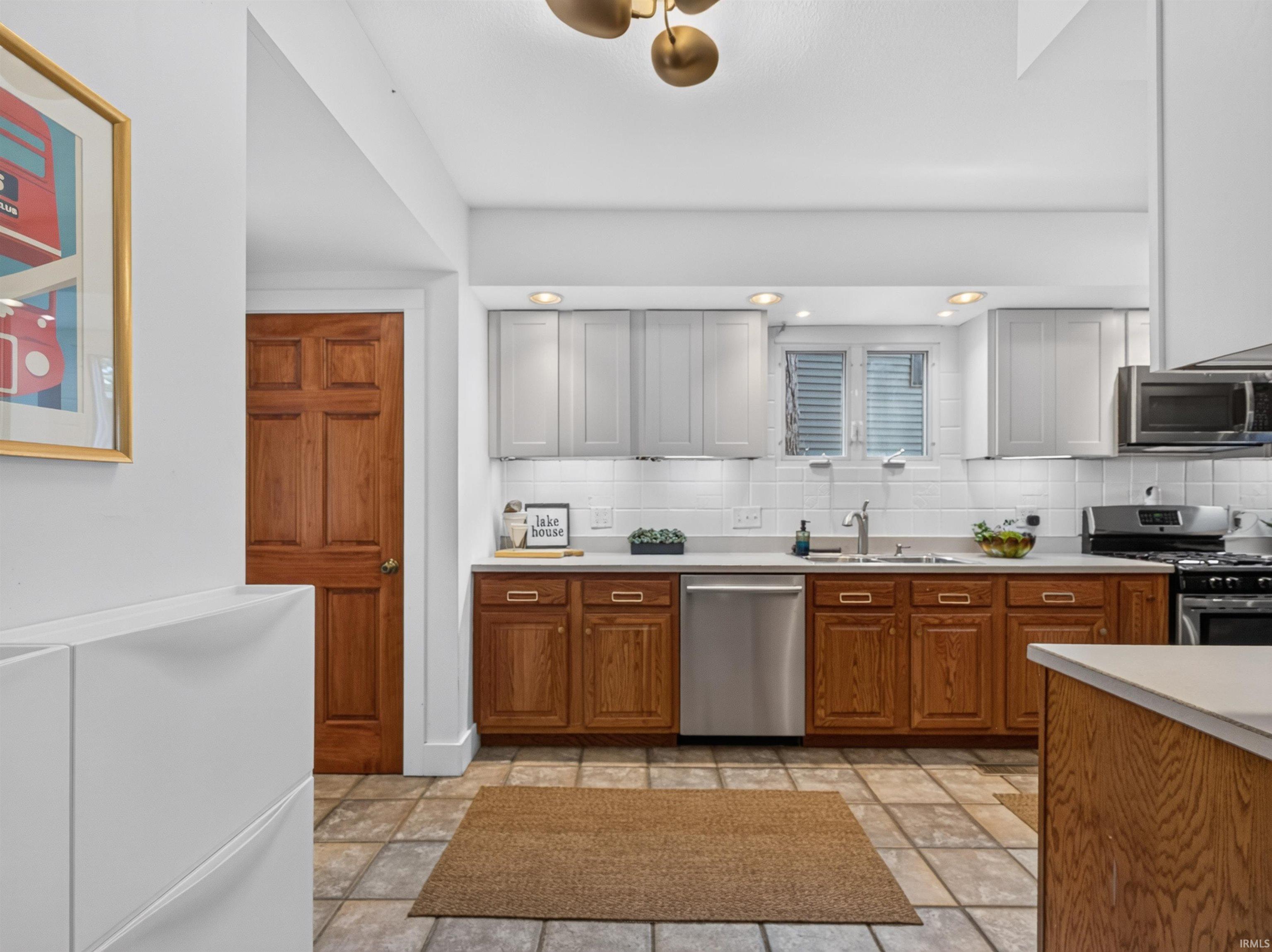 Kitchen featuring a white subway tile backsplash, stainless steel appliances, and a window above the sink