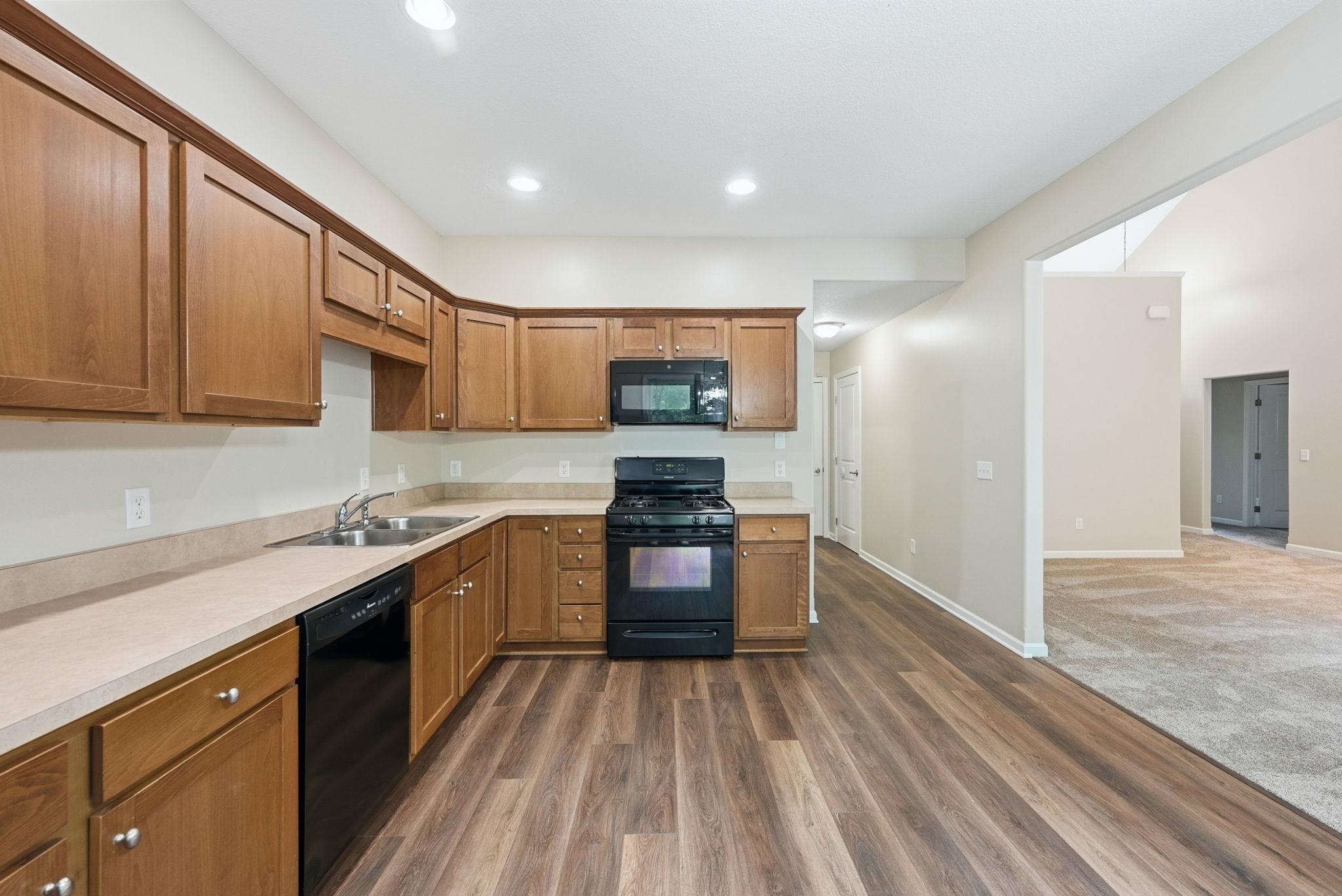 Kitchen featuring wood-finish flooring, recessed lighting, and a full suite of black appliances