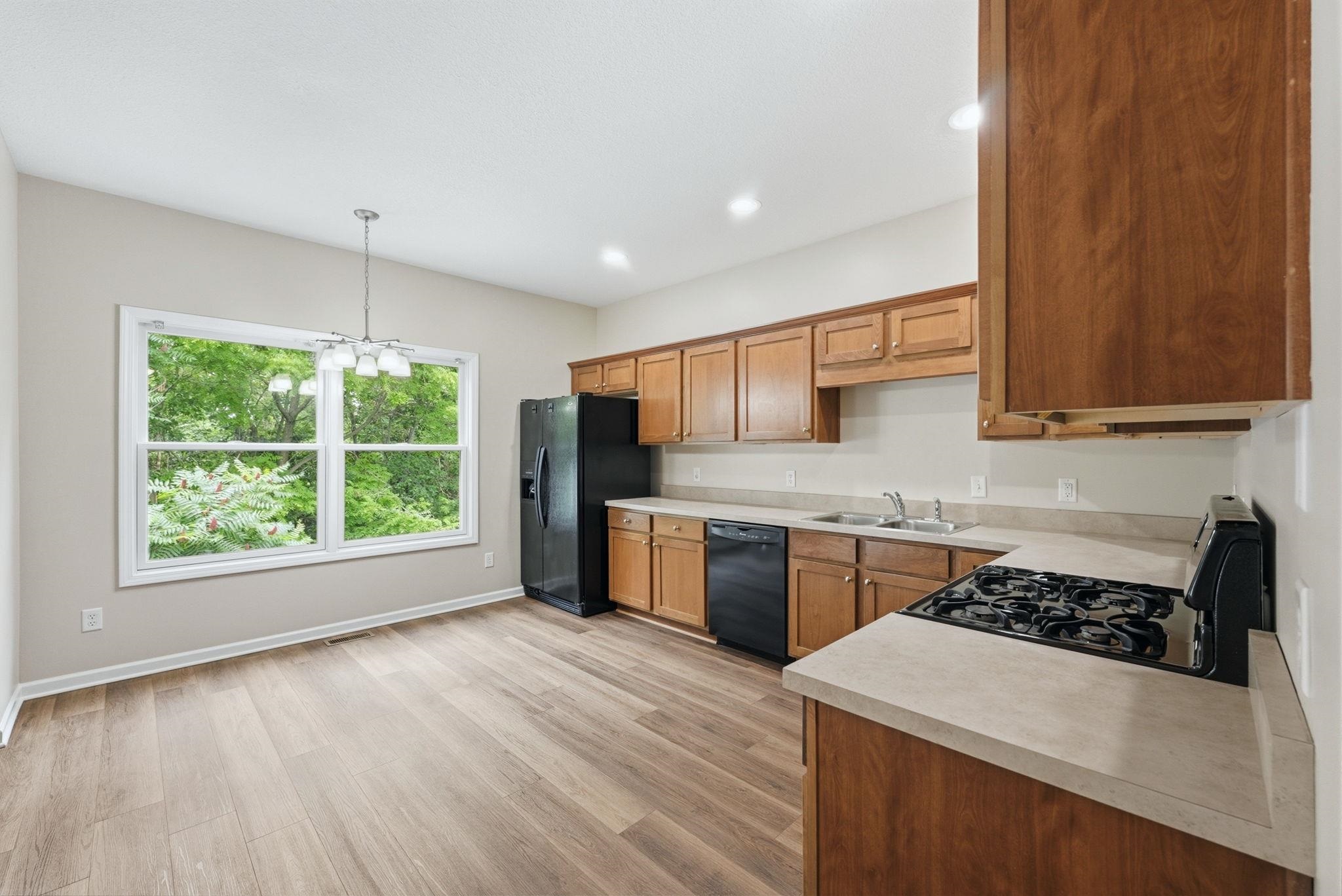 Kitchen featuring wood-finish cabinetry, black appliances, and light-toned countertops