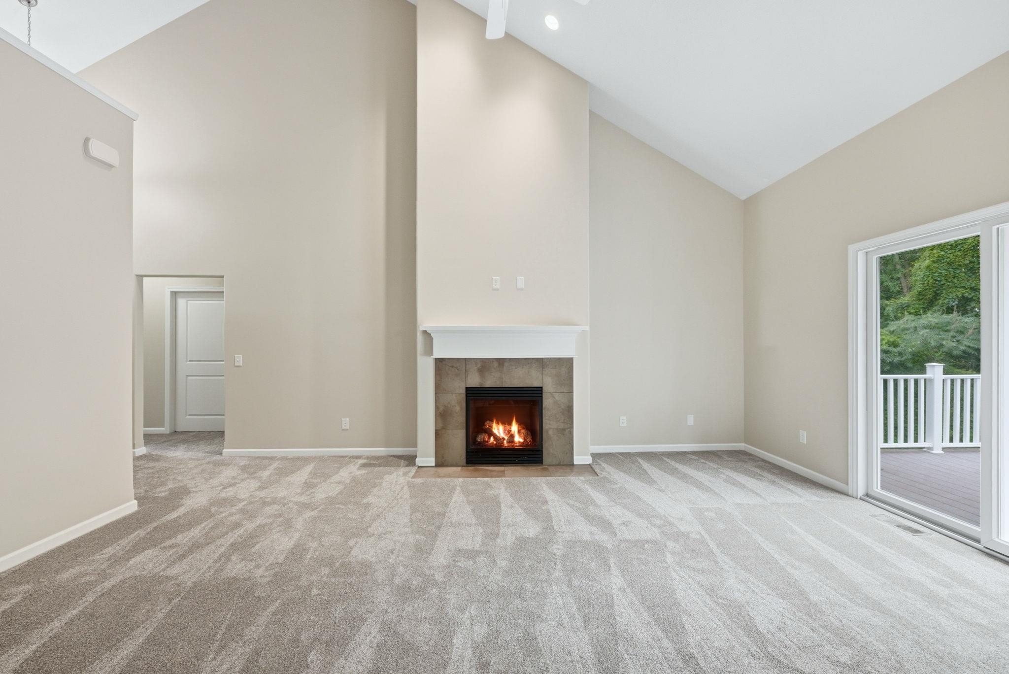 Spacious living area featuring a vaulted ceiling and a fireplace with a tile surround and white mantel