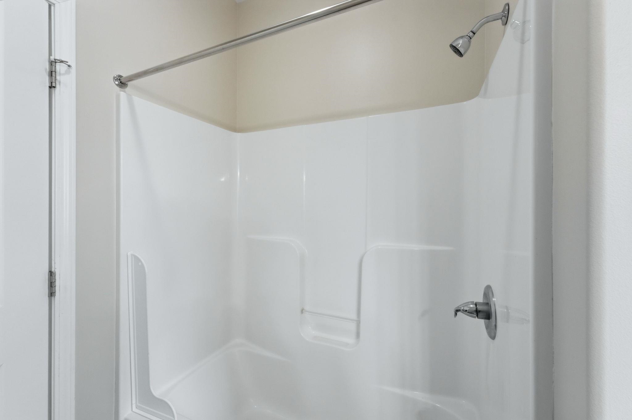 White fiberglass tub and shower combination with integrated shelving