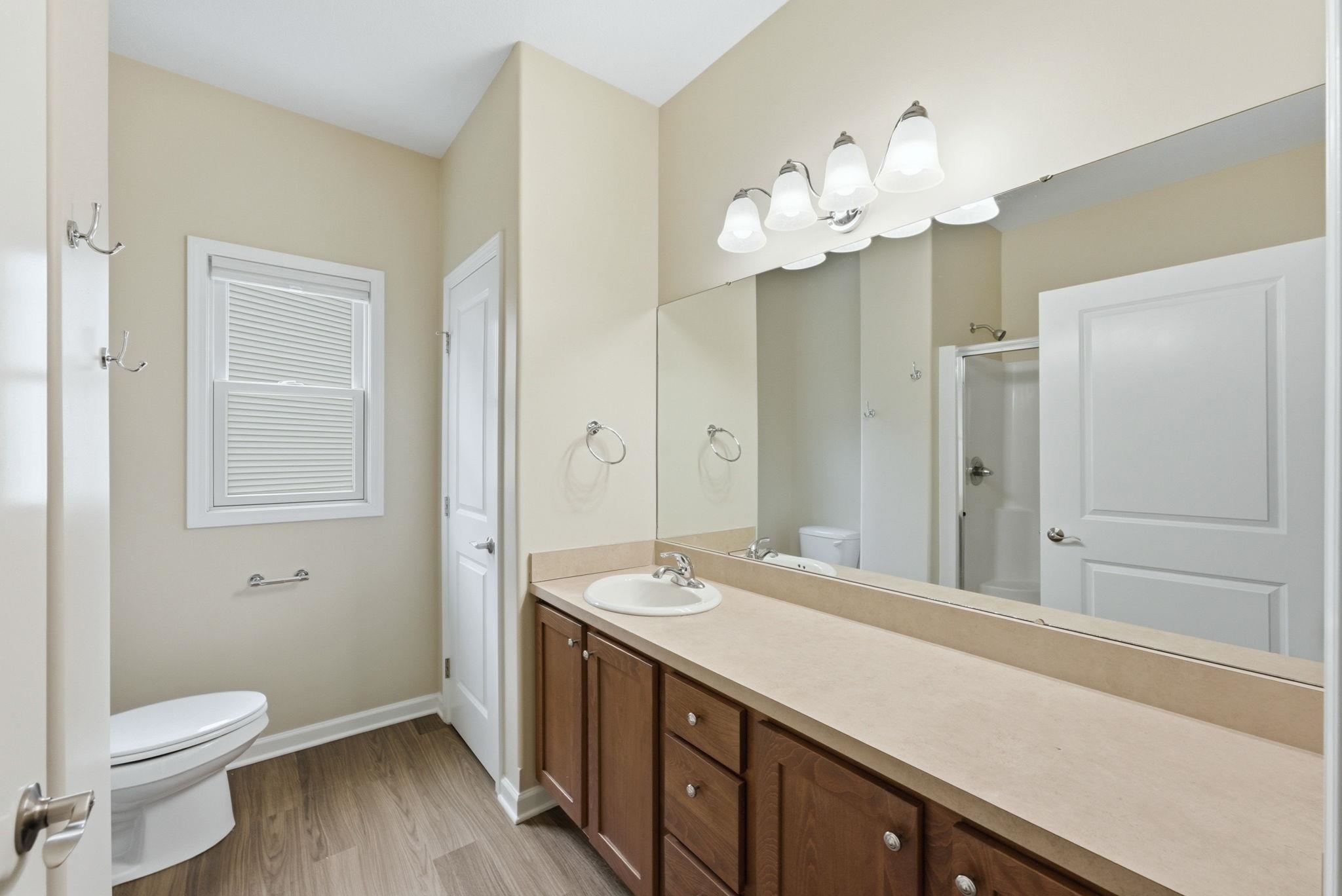 Bathroom vanity with single sink, extended countertop, and wood-finish cabinetry