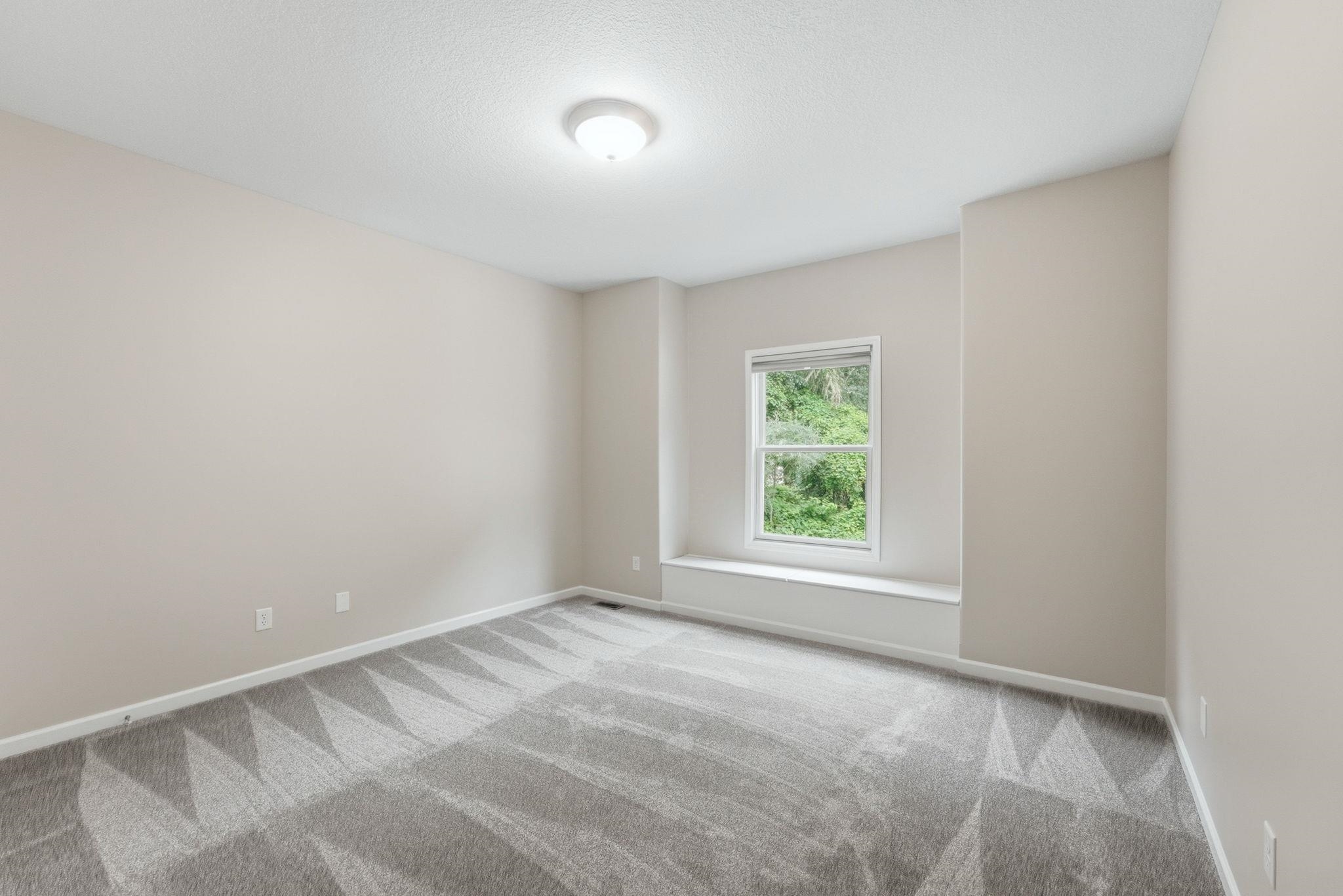 Room featuring a window seat, neutral wall color, and patterned carpet