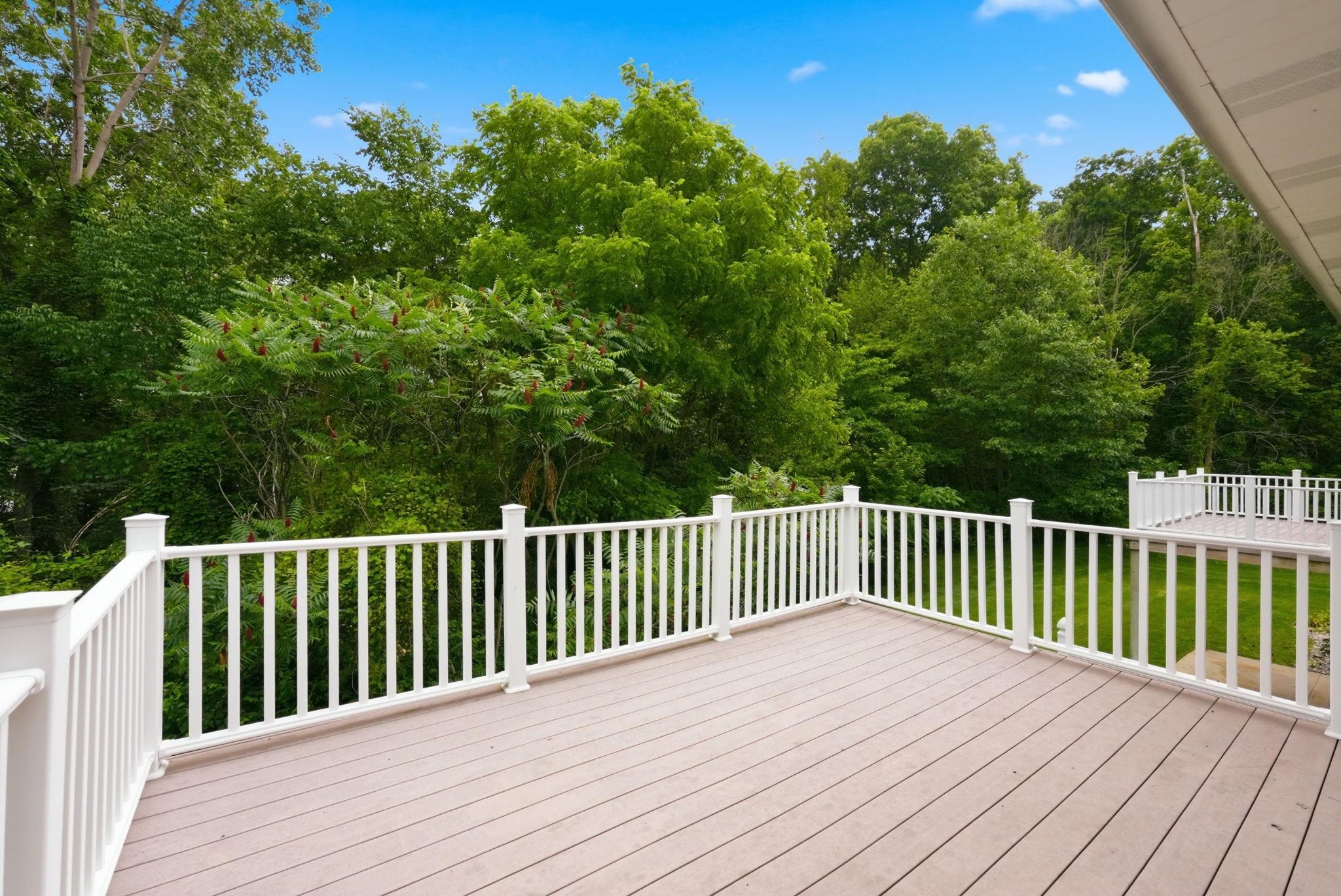 Expansive outdoor deck featuring wood-finish flooring and white railings