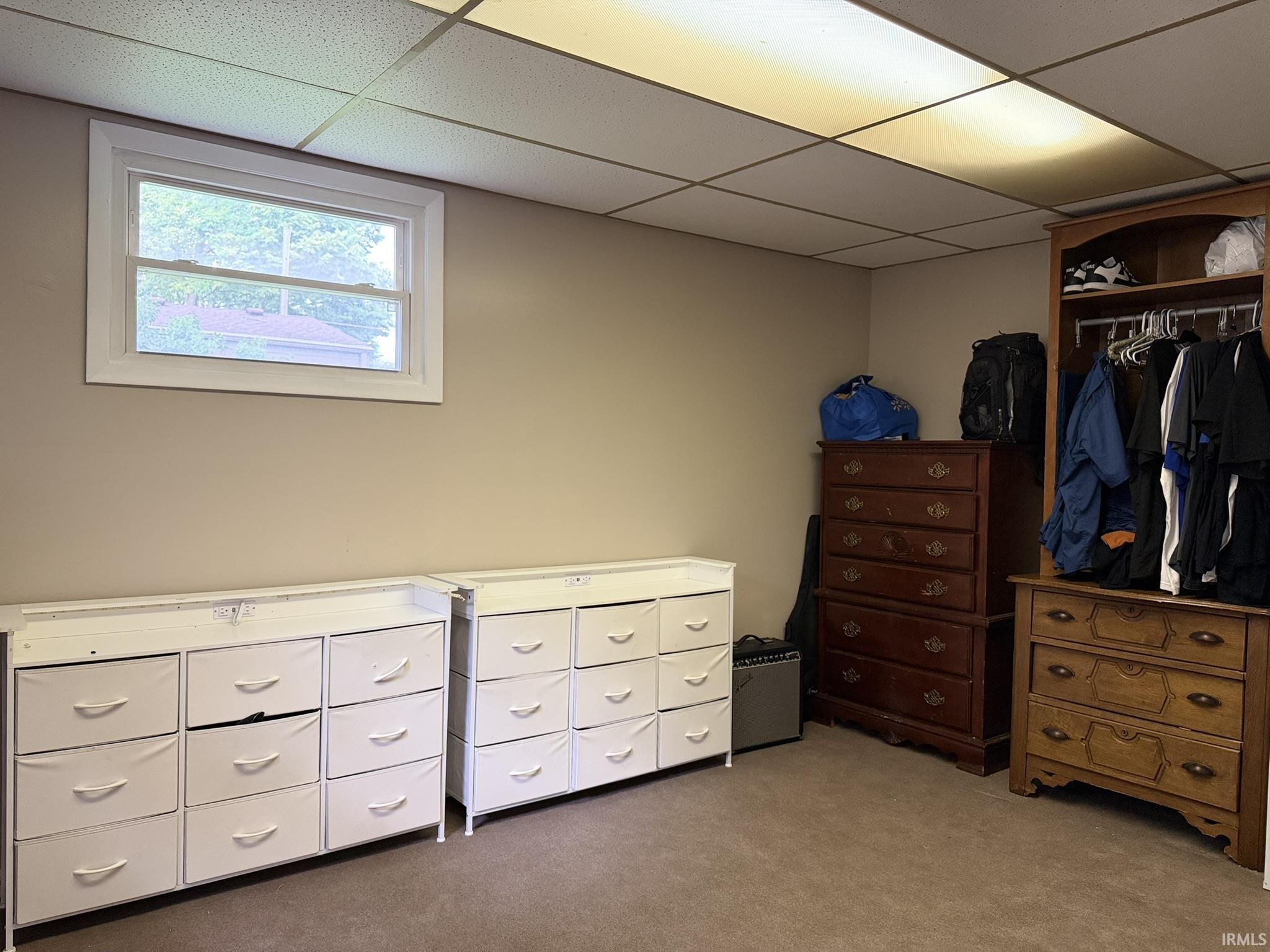 Recessed window with white trim, tan wall paint, and suspended ceiling tiles