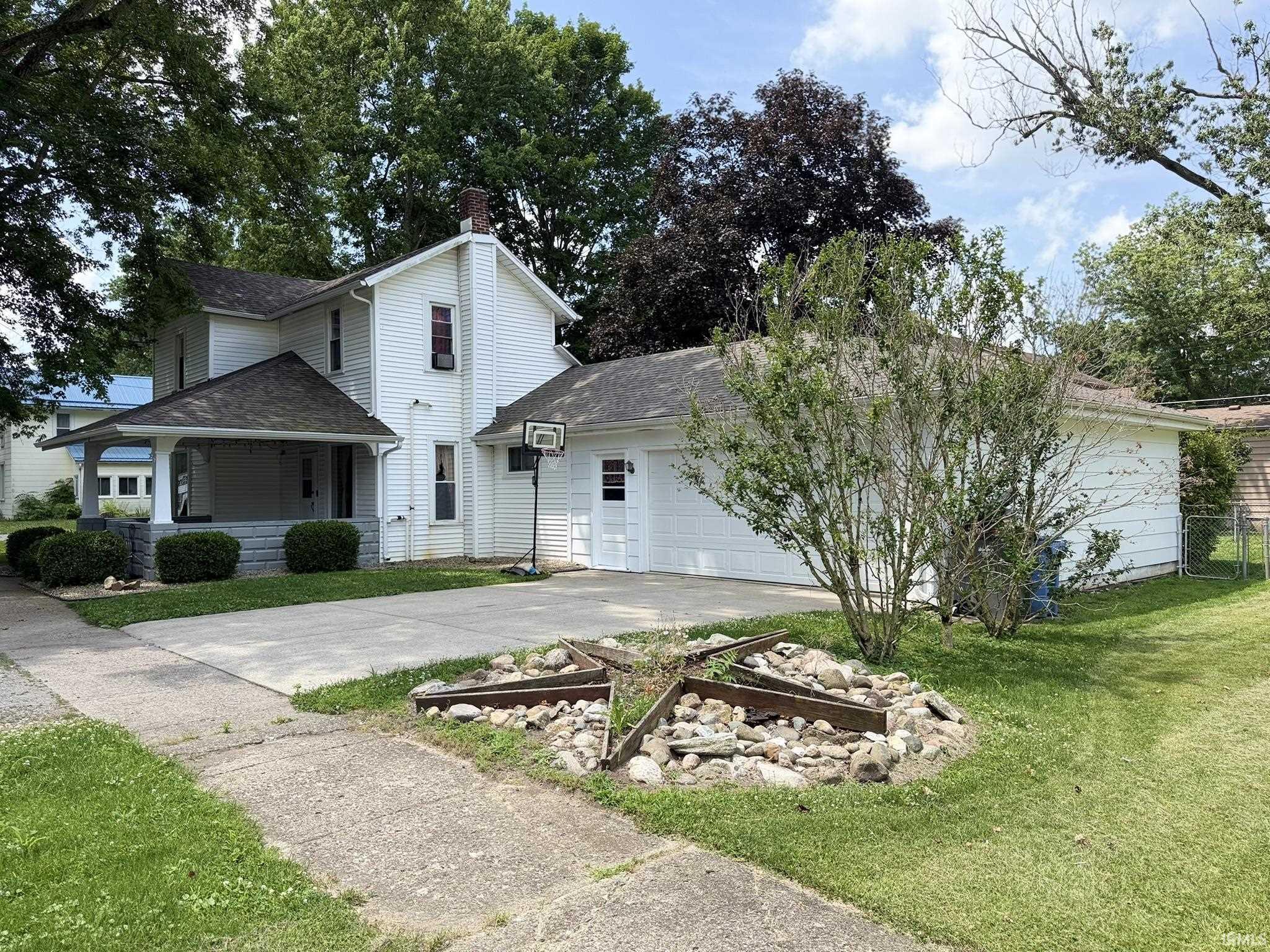 Two-story residence with a covered front porch featuring square columns and a full-width driveway leading to an attached two-car garage