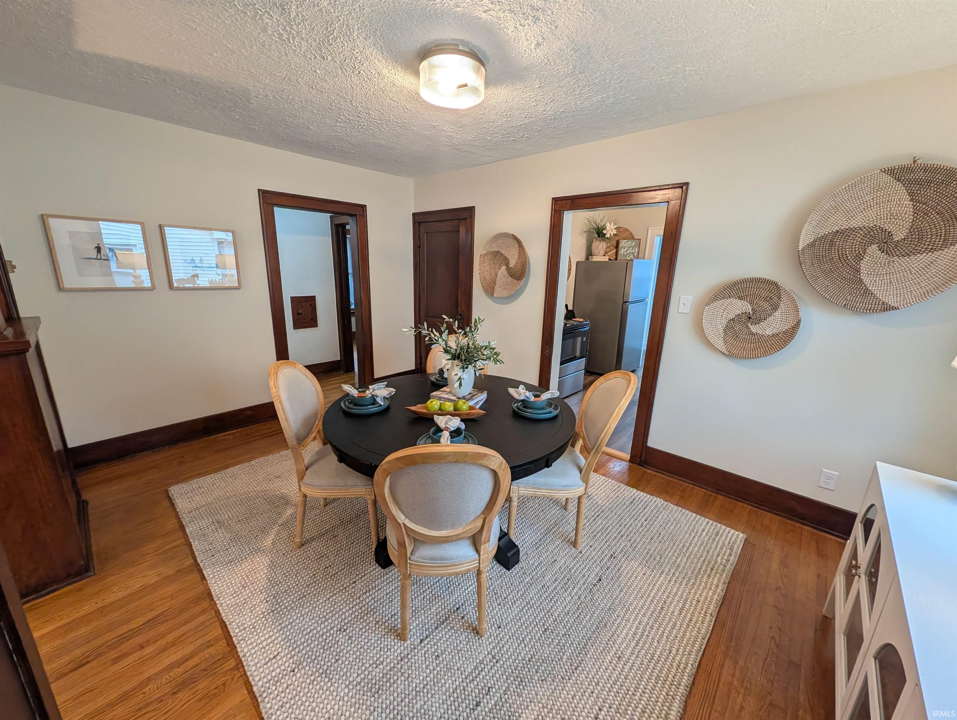 Dining area featuring wood-finish flooring, light-toned wall paint, dark wood trim, and a ceiling-mounted light fixture