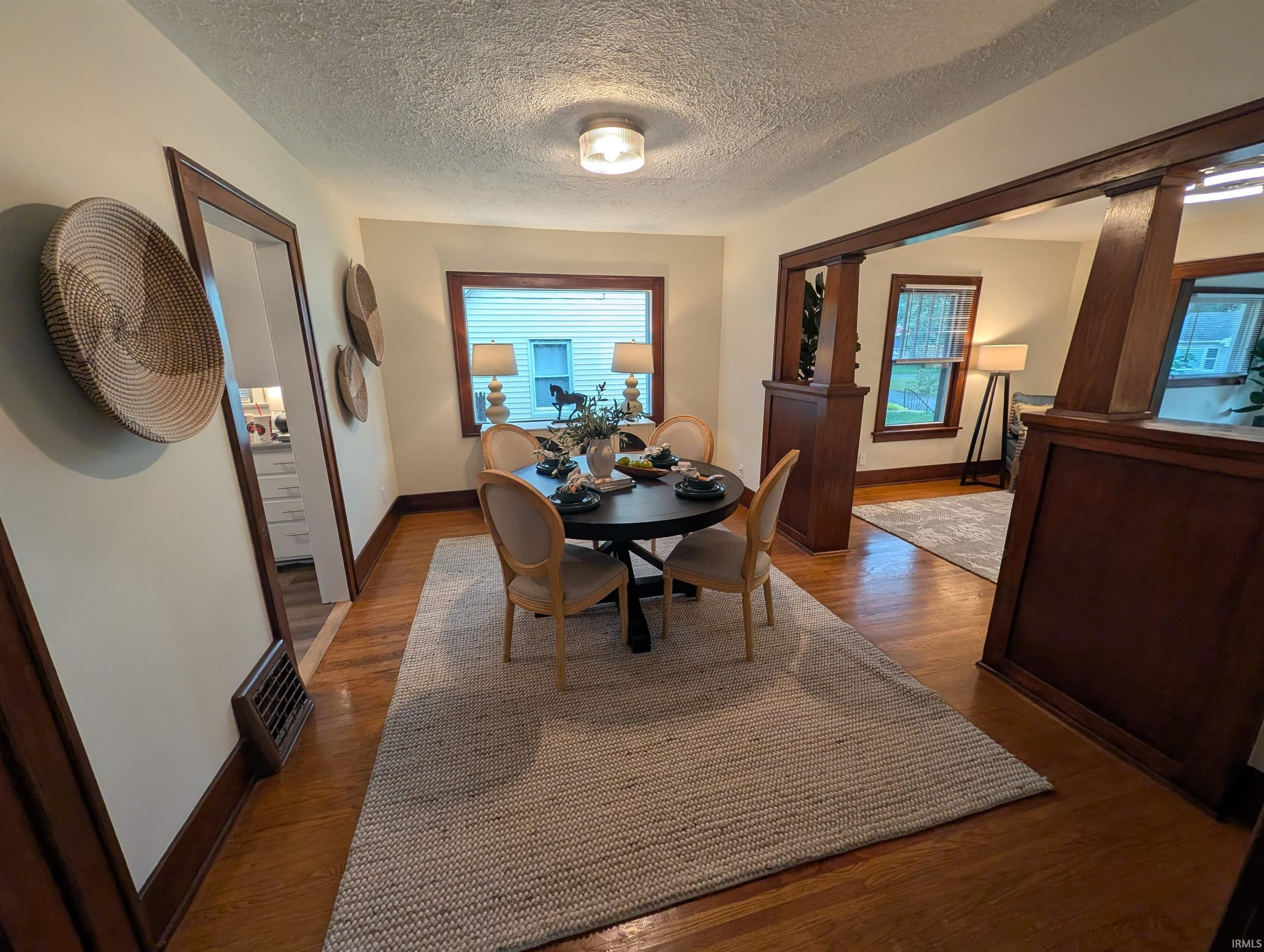 Hardwood flooring extends throughout this dining area, featuring substantial wood trim and framing around doorways and windows