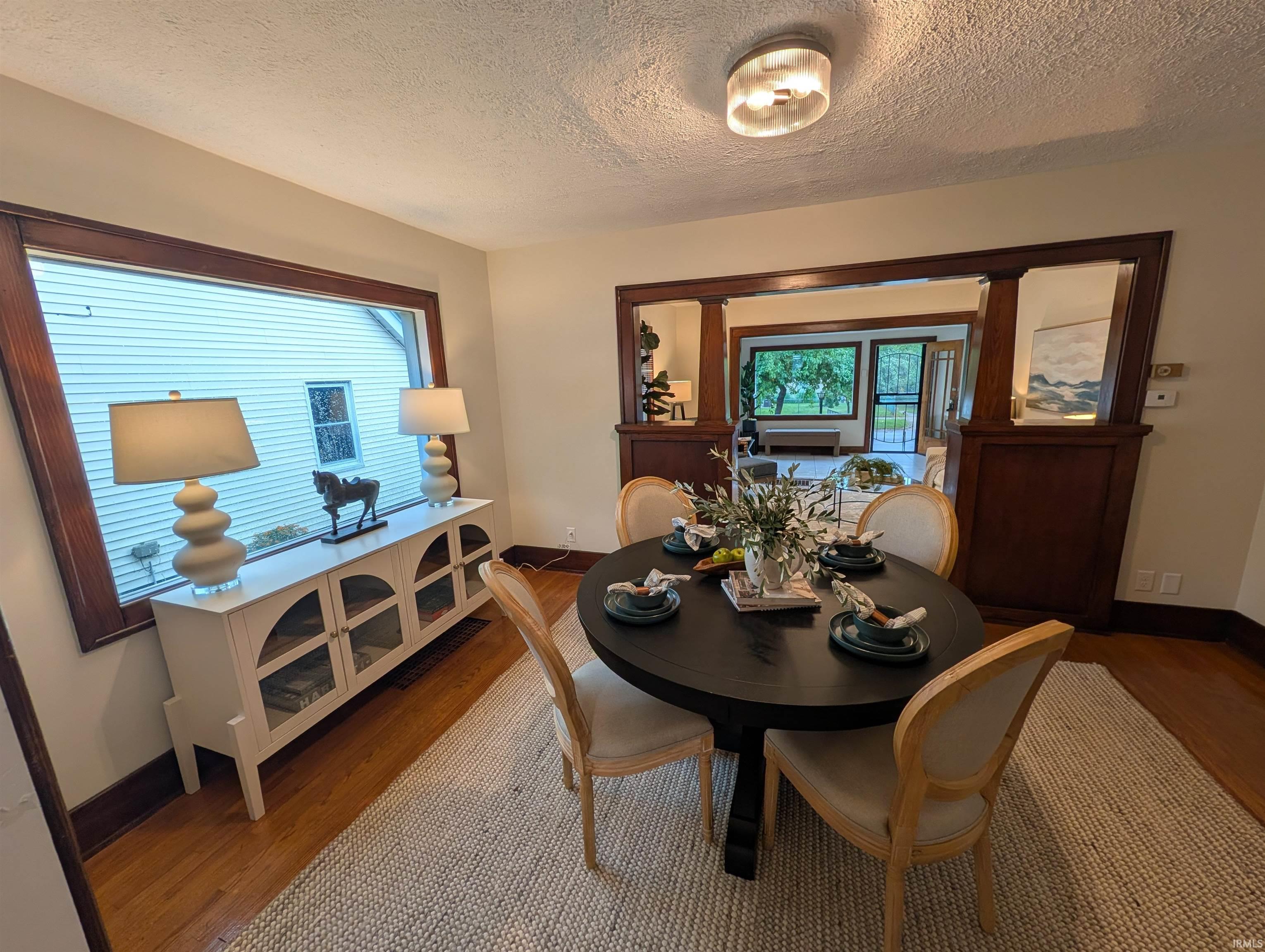 Hardwood flooring underfoot, with a large window featuring dark wood trim, and a built-in architectural feature with wood paneling and mirrors
