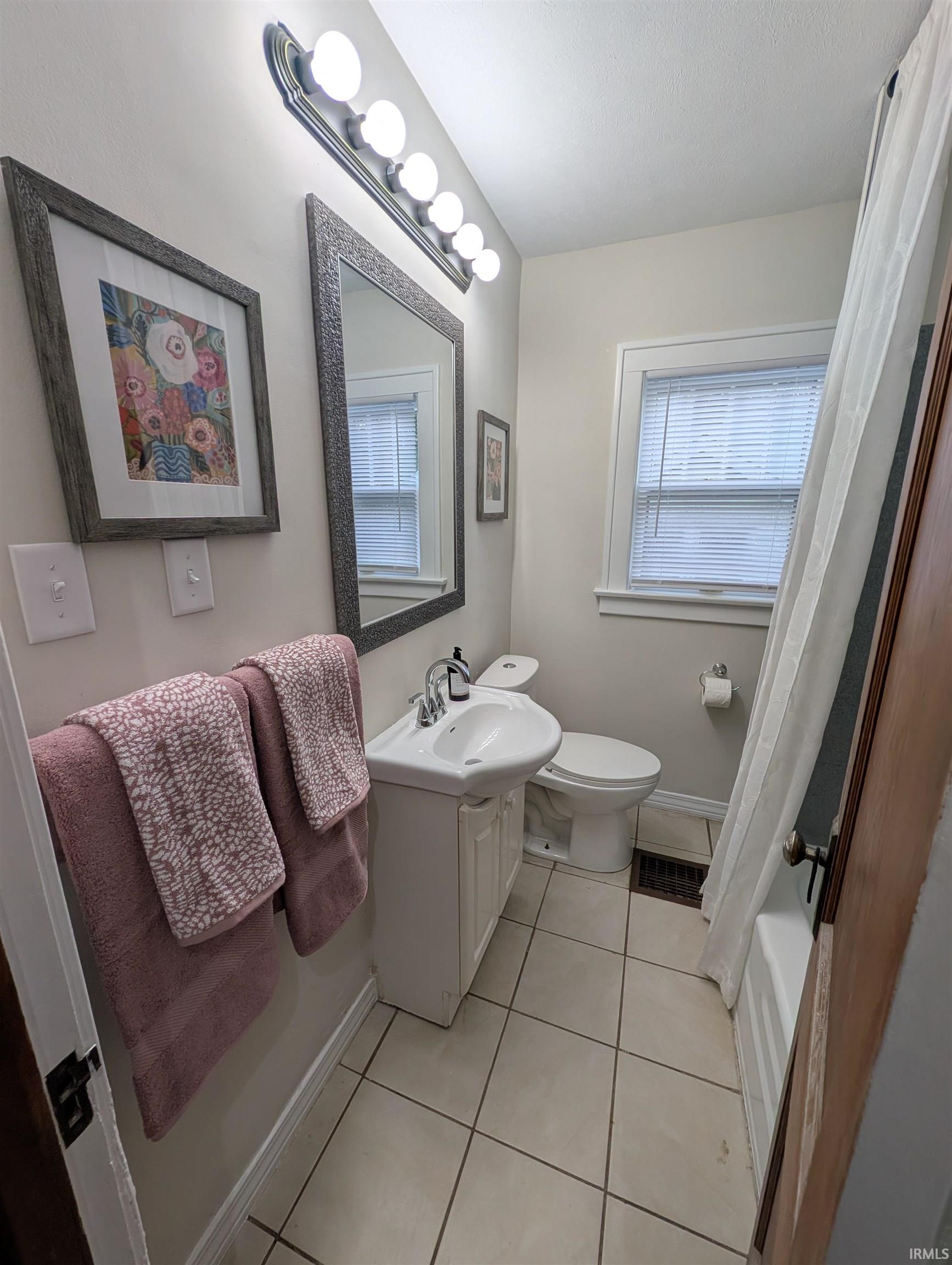 Bathroom with a single vanity, white ceramic sink, and a framed mirror