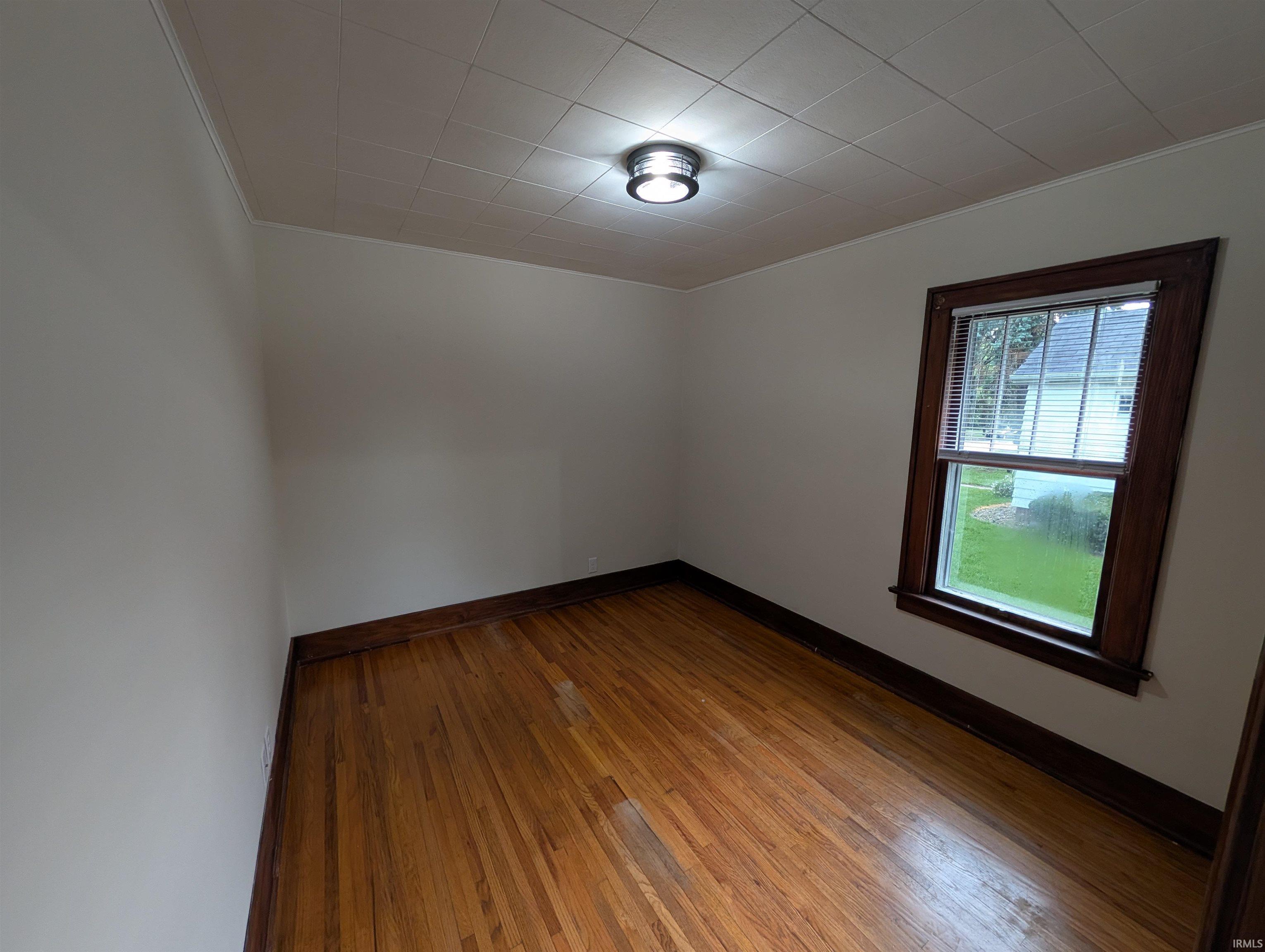 Hardwood flooring, painted walls, and a single window with wood trim