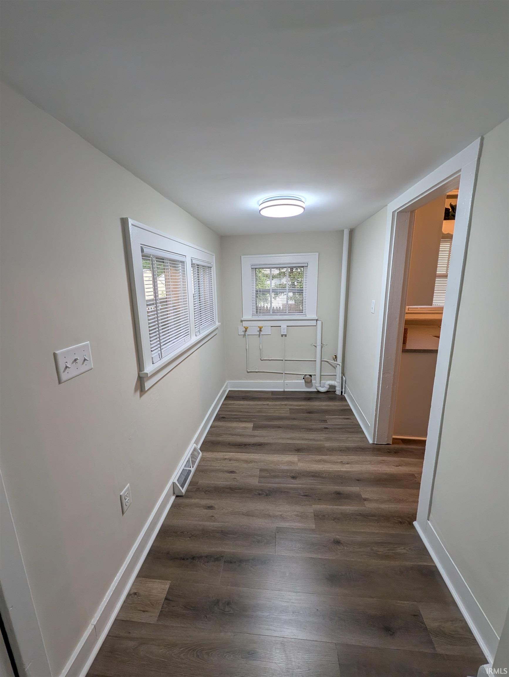 Hallway featuring wood-finish flooring and light-toned walls