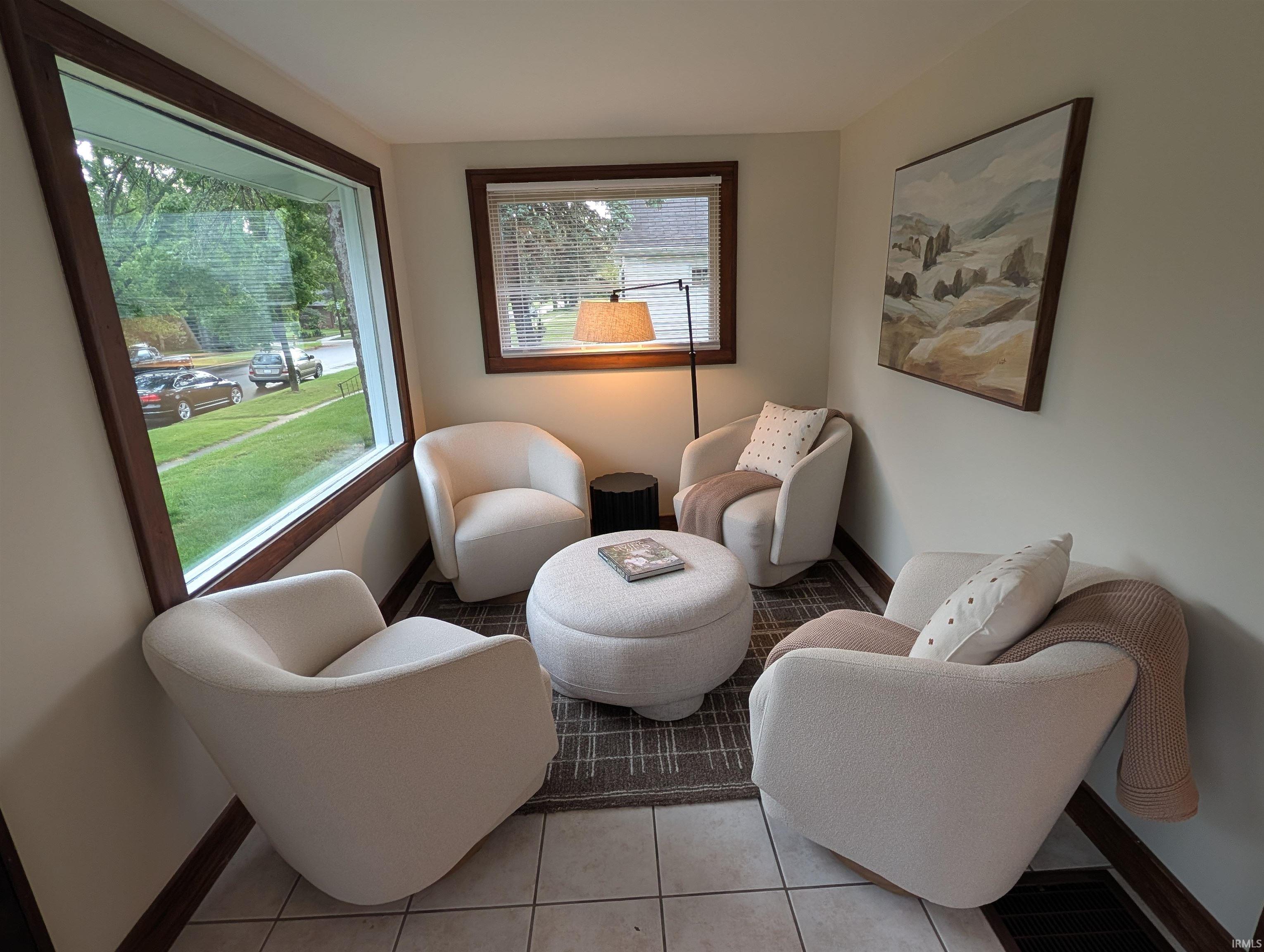 Spacious room featuring a large picture window with dark wood trim, tile flooring, and neutral wall paint