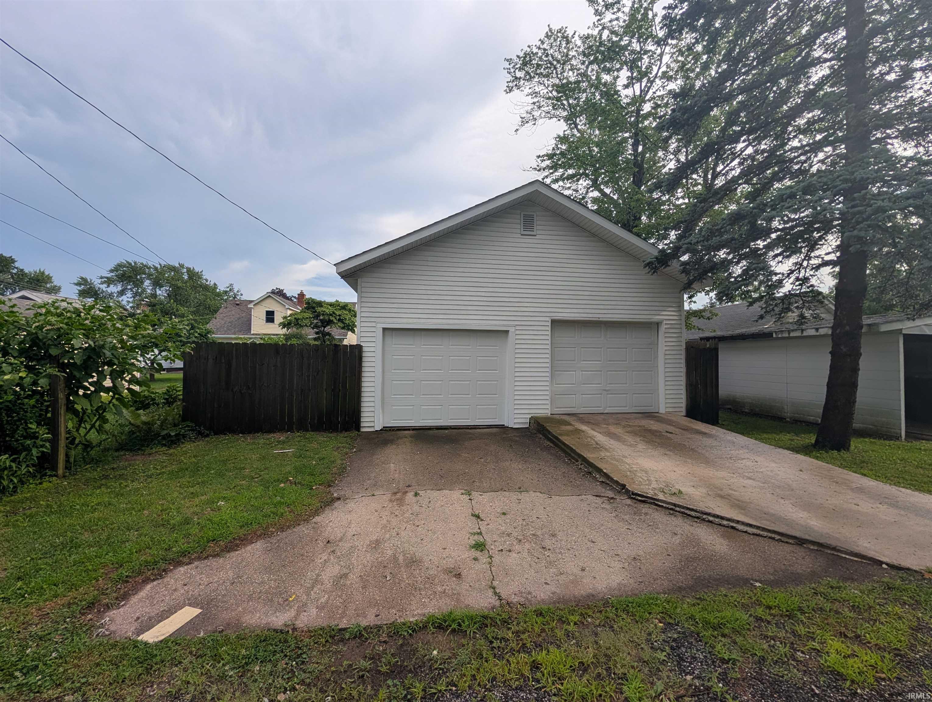 Detached two-car garage with white vinyl siding, two panel garage doors, and a concrete driveway