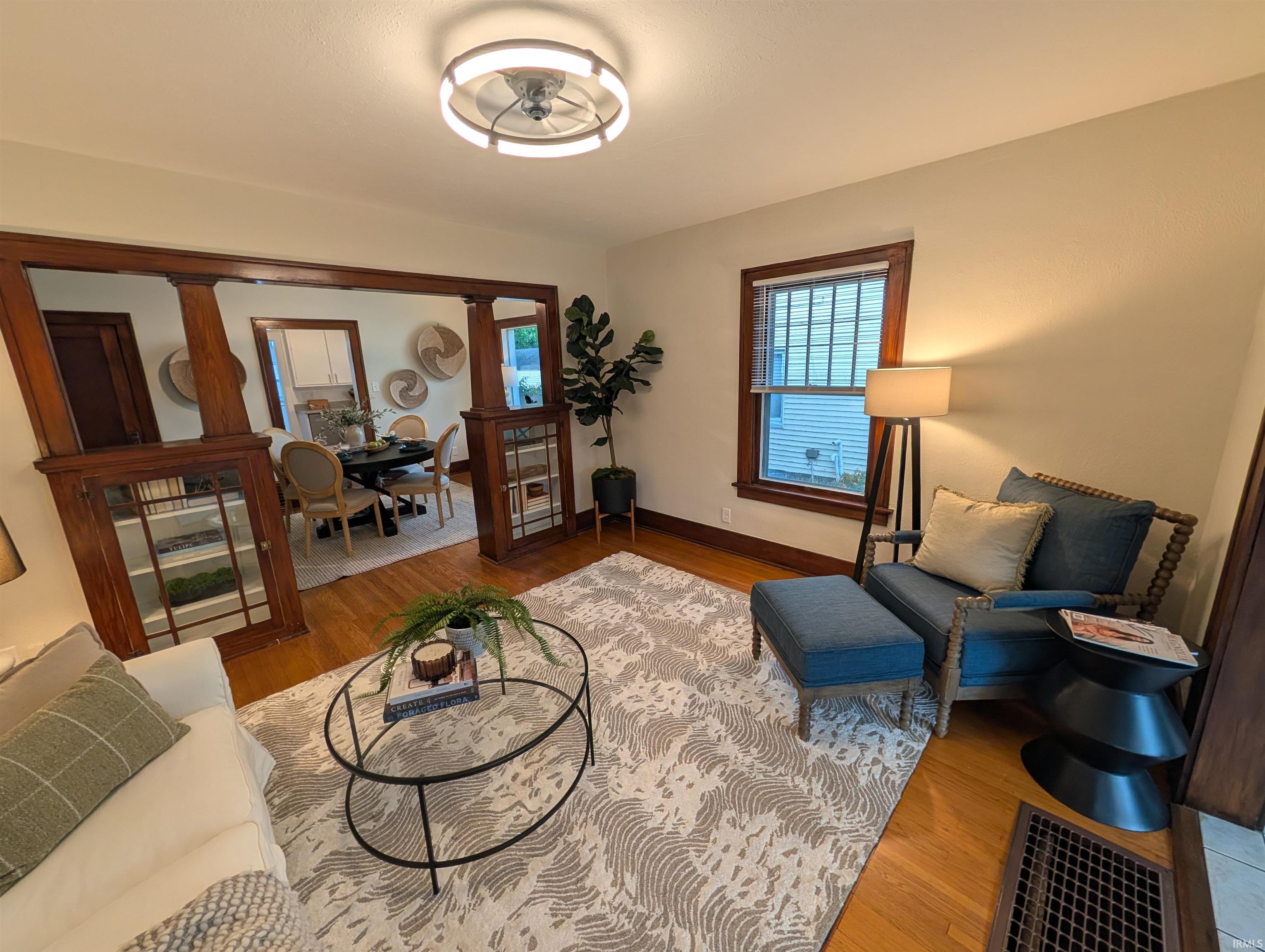 Hardwood flooring extends throughout this living space, featuring an architectural archway with built-in cabinetry and warm wood trim