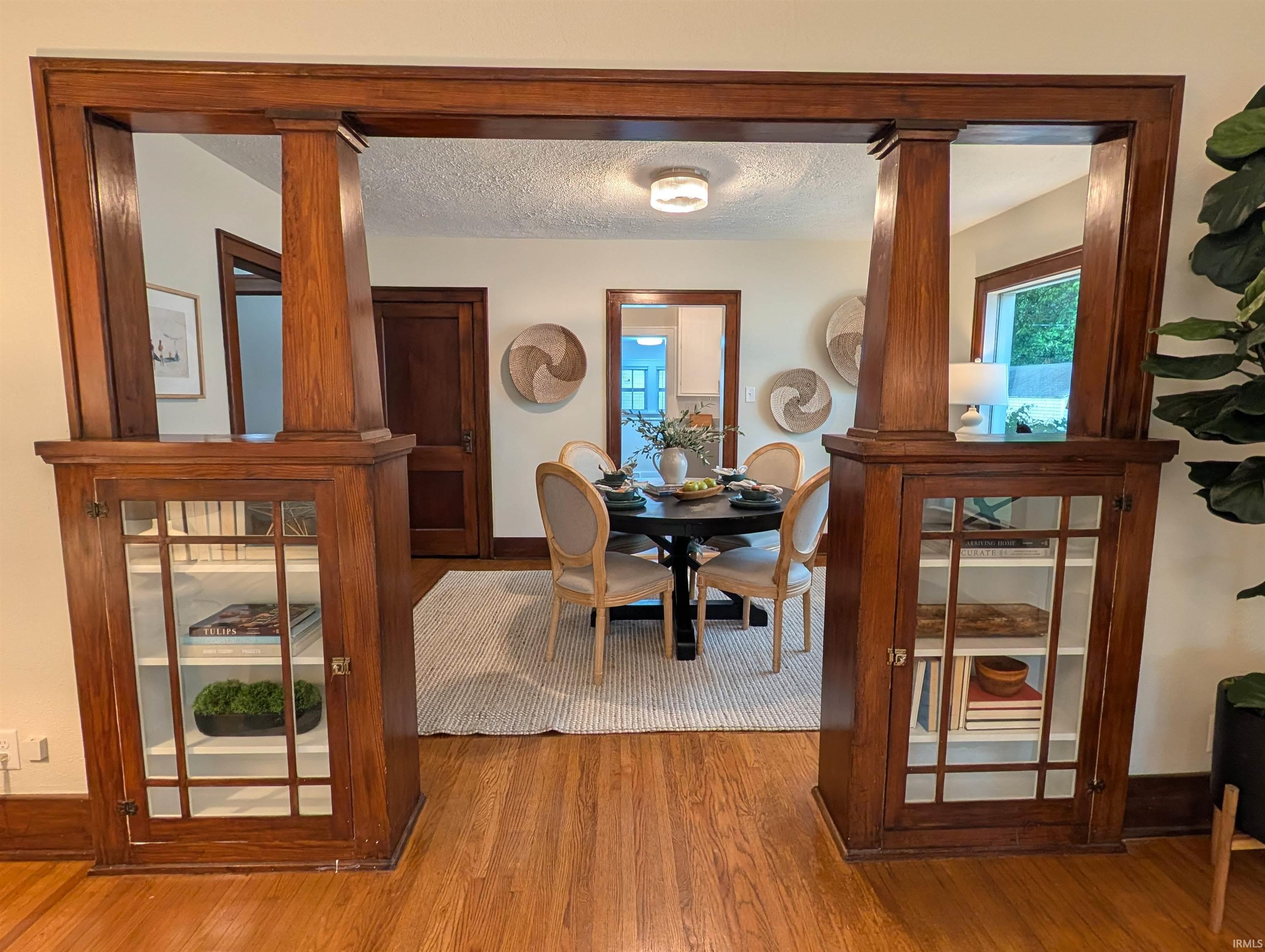 Craftsman-style wood archway with integrated display cabinetry, wood-finish flooring, and ample natural light