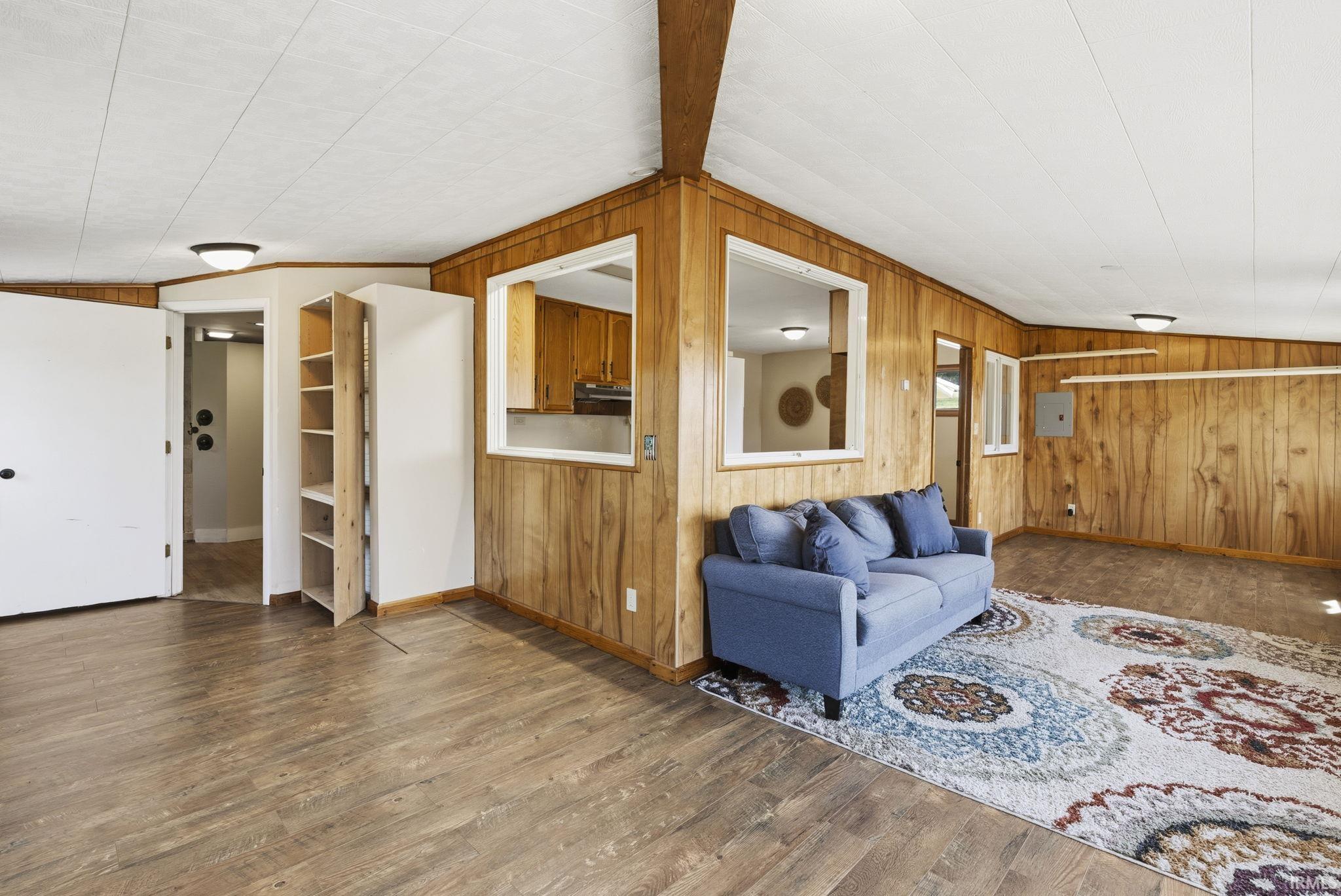 Open-concept living area featuring wood-finish flooring, wood paneling, and a drop ceiling