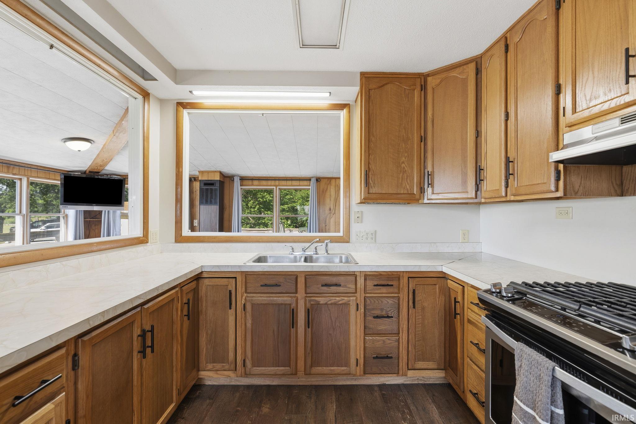 Kitchen featuring wood cabinetry, light-toned countertops, and a double basin stainless steel sink