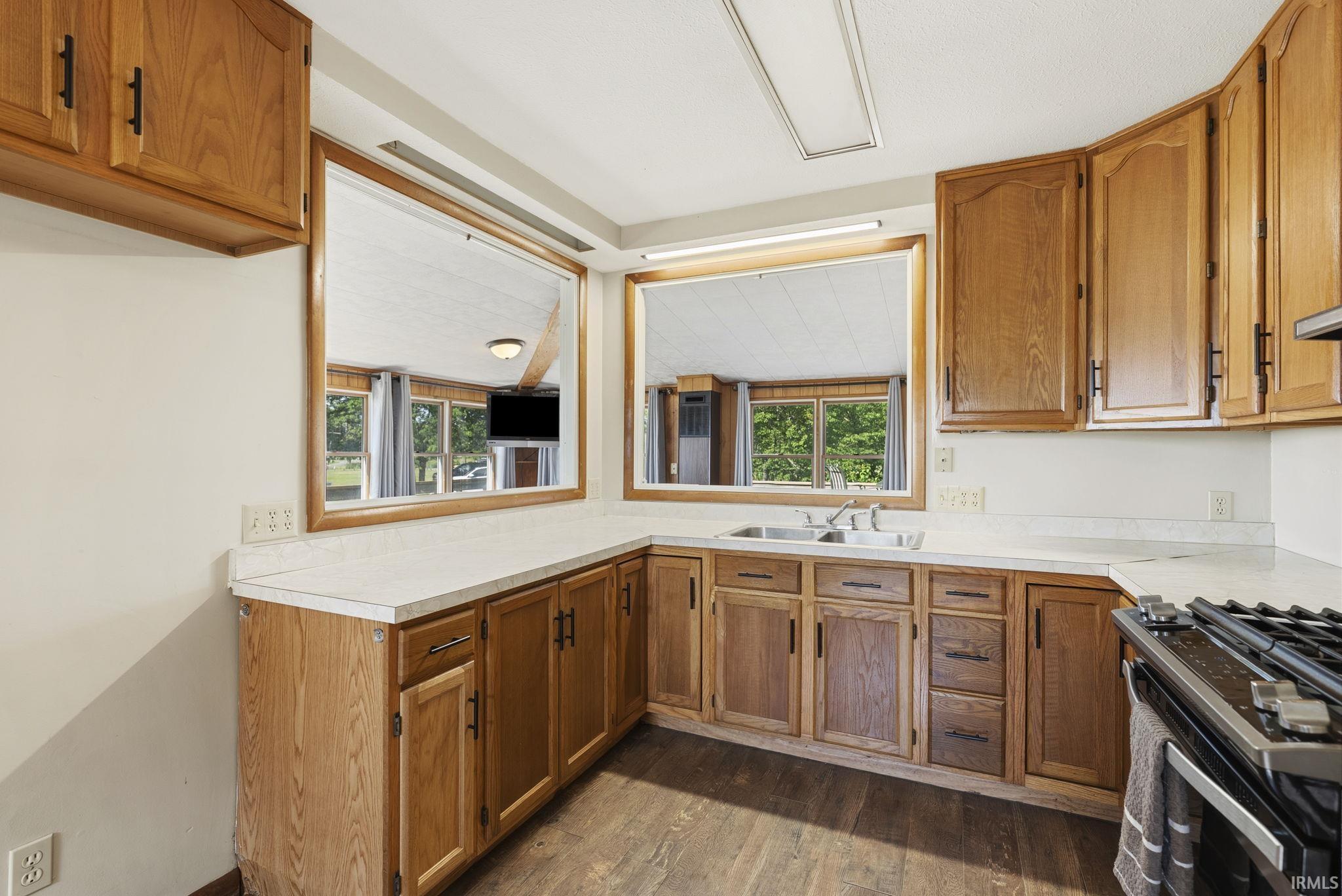 Kitchen featuring wood-finish cabinetry, light-toned countertops, and a dual-basin stainless steel sink