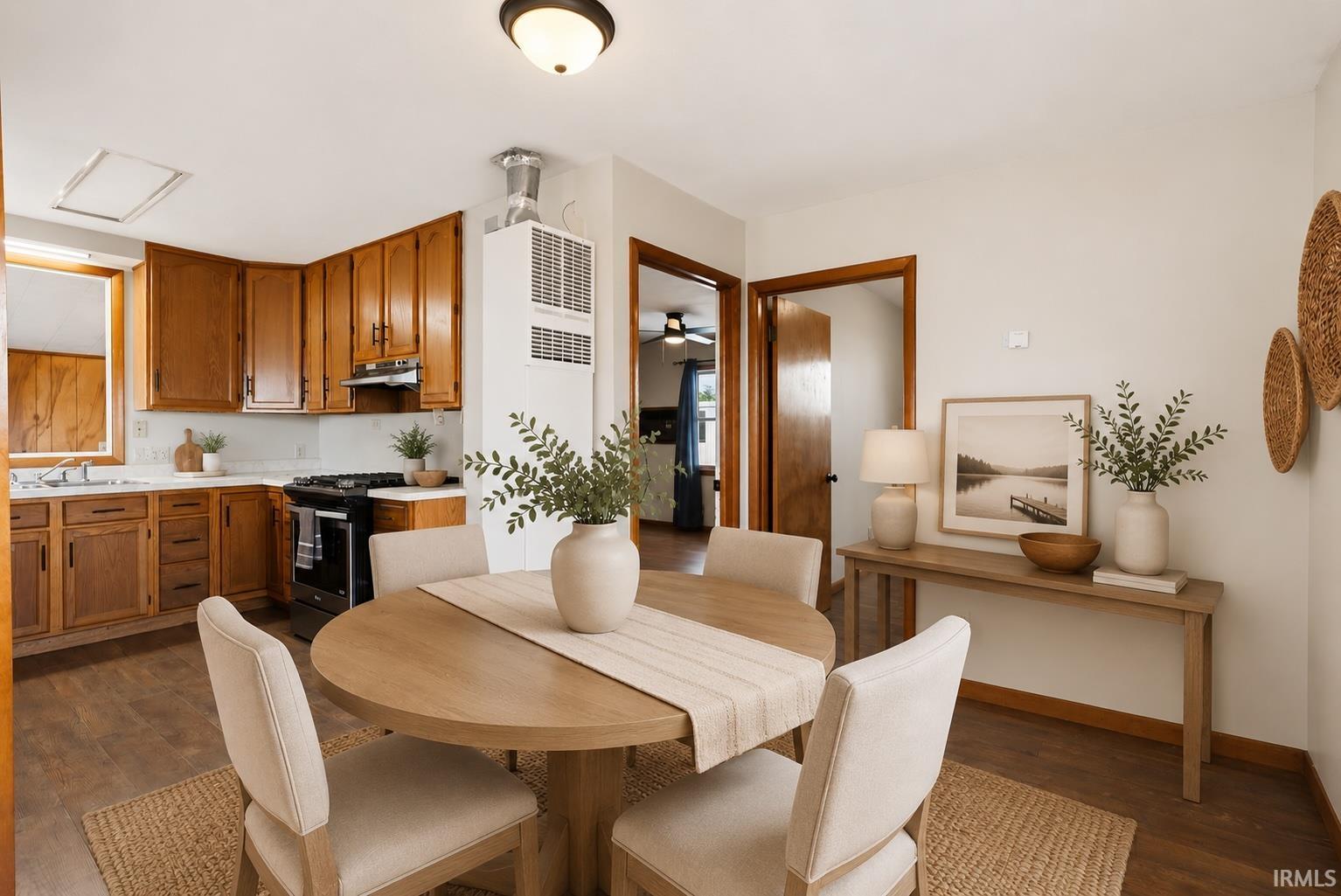 Bright kitchen area featuring wood-finish flooring, a ceiling-mounted light fixture, wood cabinetry, and white countertops
