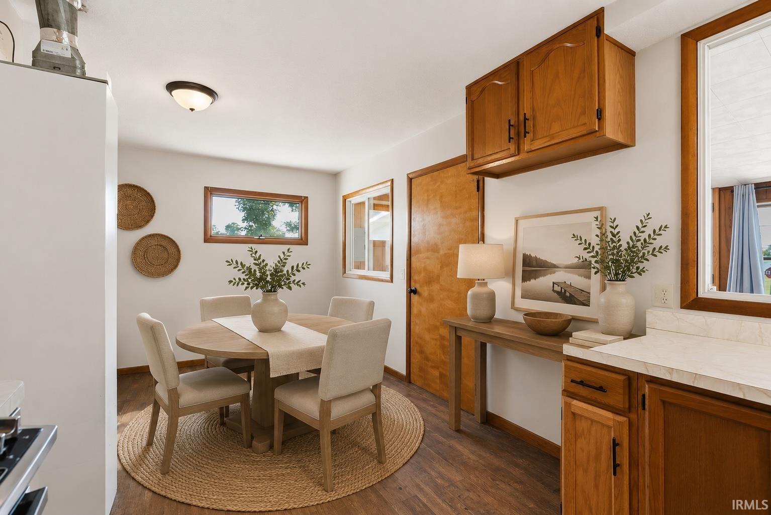 Dining area featuring wood-finish flooring, two windows with wood trim, and a ceiling-mounted light fixture