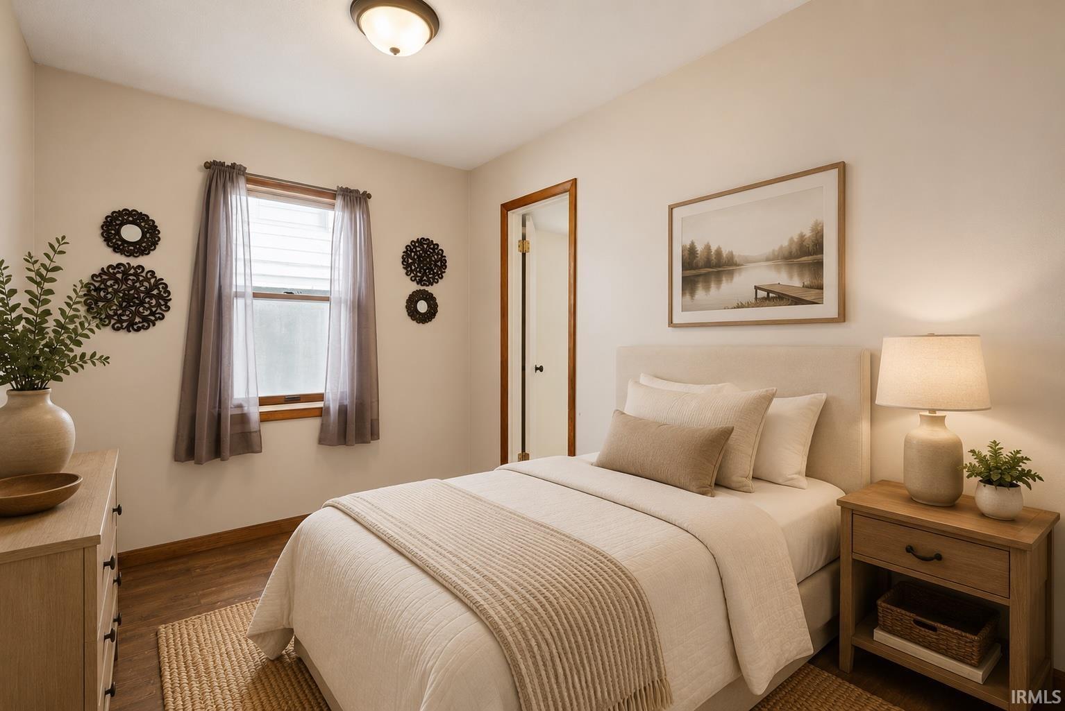 Bedroom featuring wood-finish flooring, a double-hung window with wood trim, and neutral wall tones