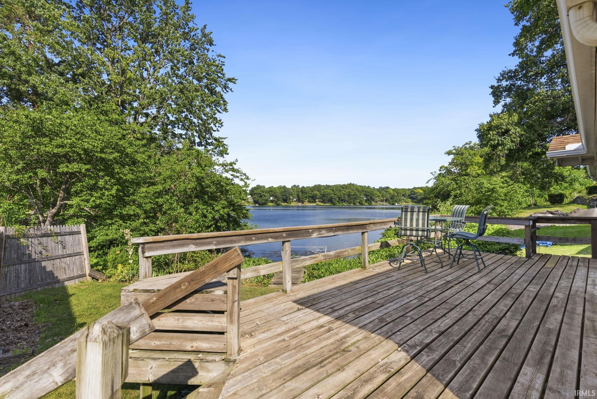 Wood deck overlooking a body of water with a wooded shoreline